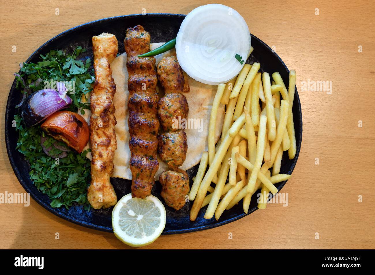 Mishkak. Nourriture populaire à Oman, qui est grillé morceaux de viande marinée, poulet, mouton et bœuf sur de longs bâtonnets de bois avec pommes de terre frites, citron et Banque D'Images