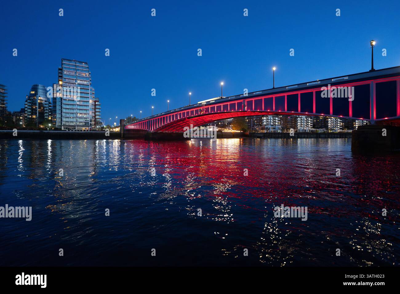 Crépuscule sur le pont de Wandsworth à Londres. Les lumières rouges se reflètent dans la Tamise, créant une scène vibrante. Banque D'Images