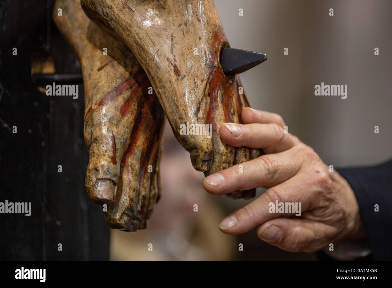 Sahagun, Léon, Espagne. 18 avril 2025. Membre de la fraternité de notre Père Jésus de Nazareth et patronage de Saint Joseph, touche avec respect les pieds de l'image articulée du Christ crucifié, lors de la messe à l'église de San Lorenzo et de la procession funéraire Sainte dans les rues de Sahagun. (Crédit image : © Luis Soto/ZUMA Press Wire) USAGE ÉDITORIAL SEULEMENT ! Non destiné à UN USAGE commercial ! Banque D'Images