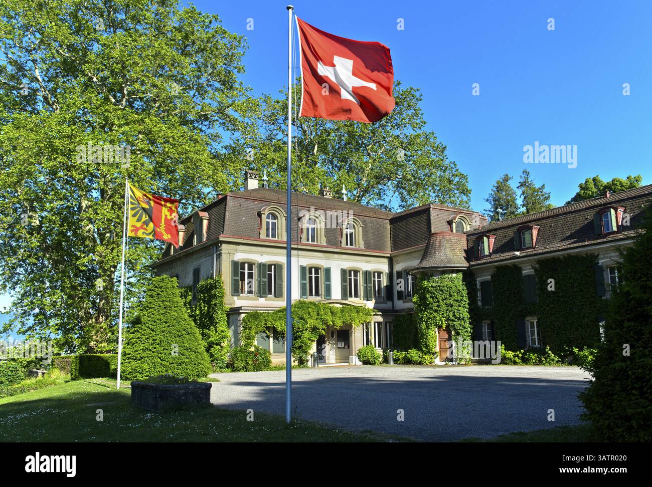 Château de Penthes avec le drapeau national suisse et le drapeau du canton de Genève dans le parc du domaine de Penthes, Pregny-Chambesy, Genève, Switze Banque D'Images
