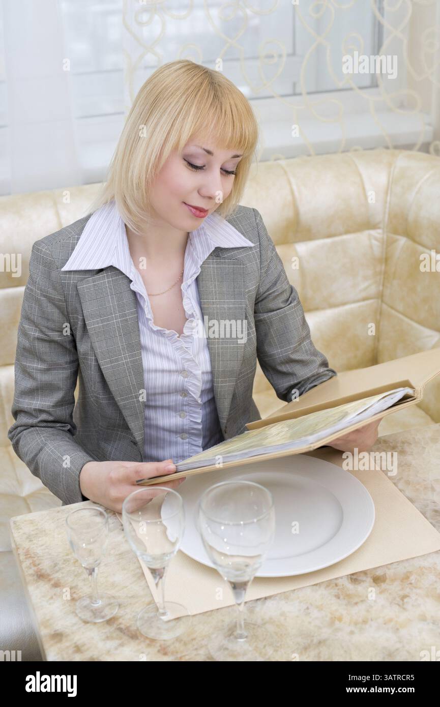 Jeune femme blonde lisant le menu au restaurant de première classe Banque D'Images
