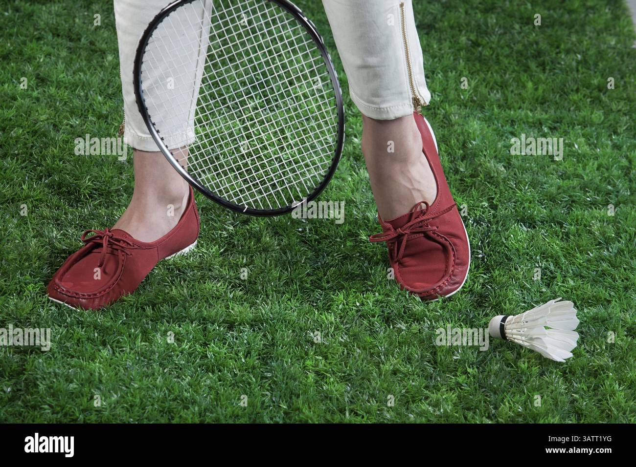 Jambes de femme, raquette de badminton et volant sur une herbe verte Banque D'Images
