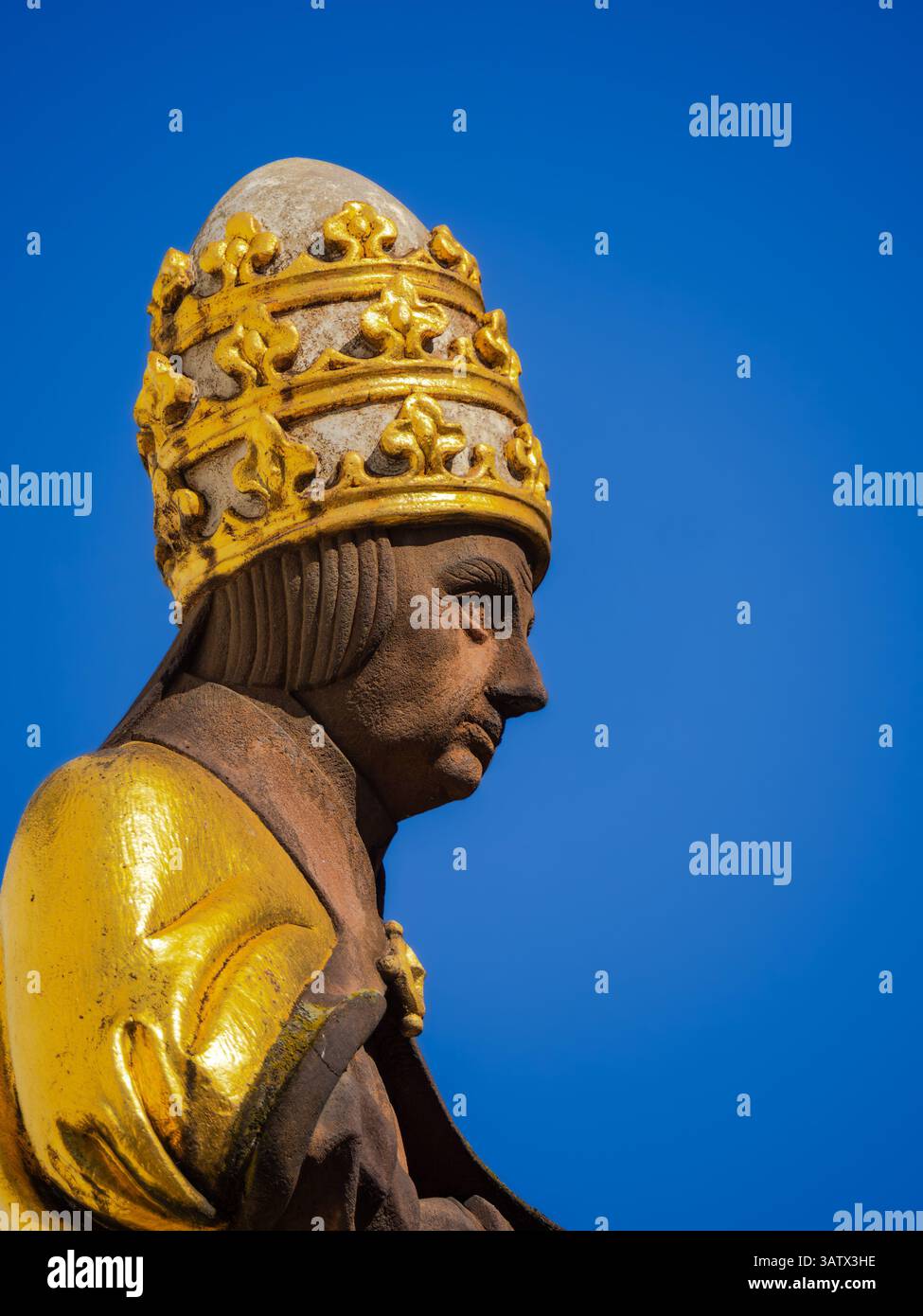 Bâle, Suisse - 2 avril 2025 : statue d'une figure religieuse historique portant une tiare papale contre un ciel bleu clair. Banque D'Images