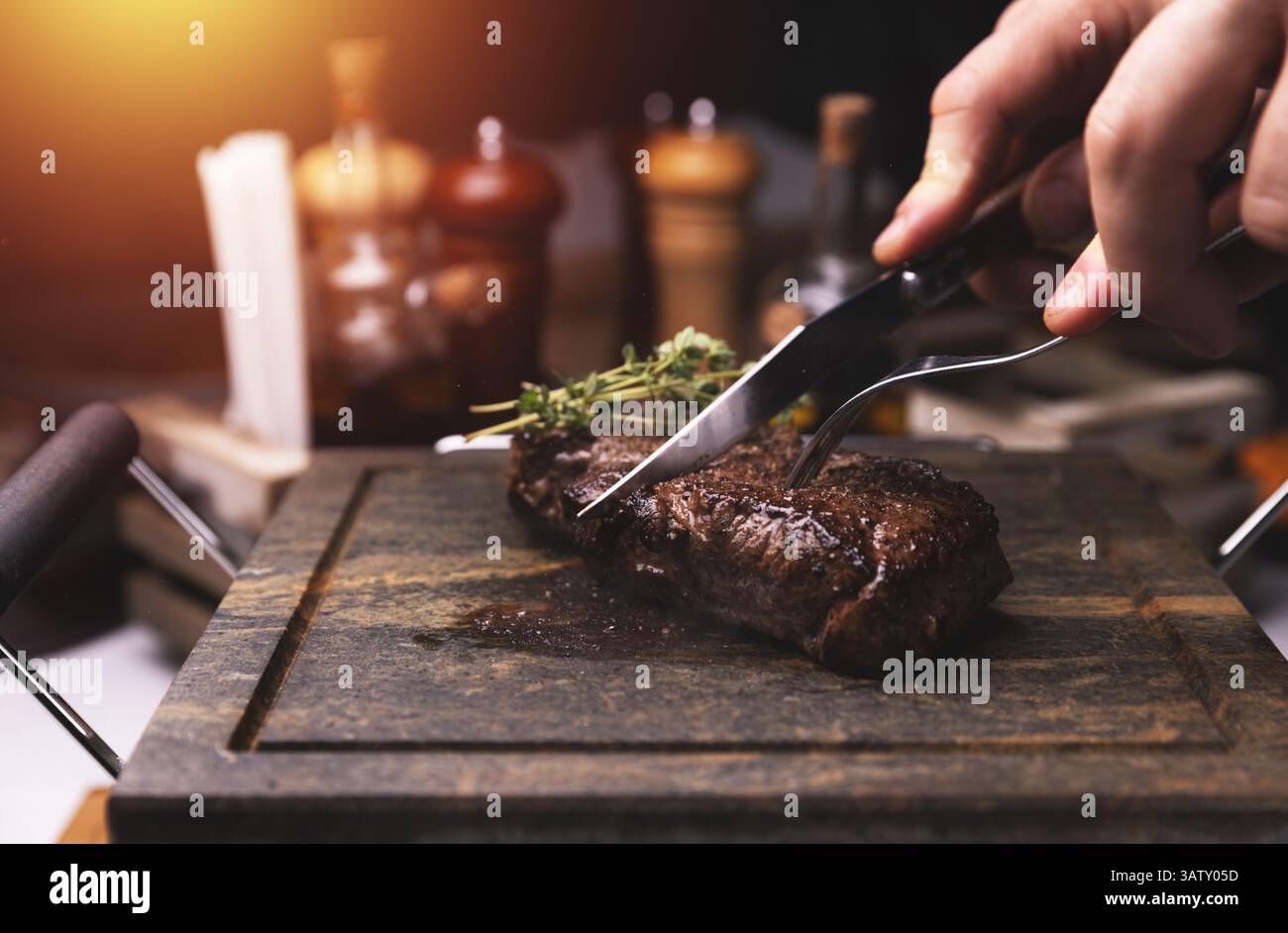 Le chef découpe des steaks grillés à bord dans la cuisine du restaurant Banque D'Images