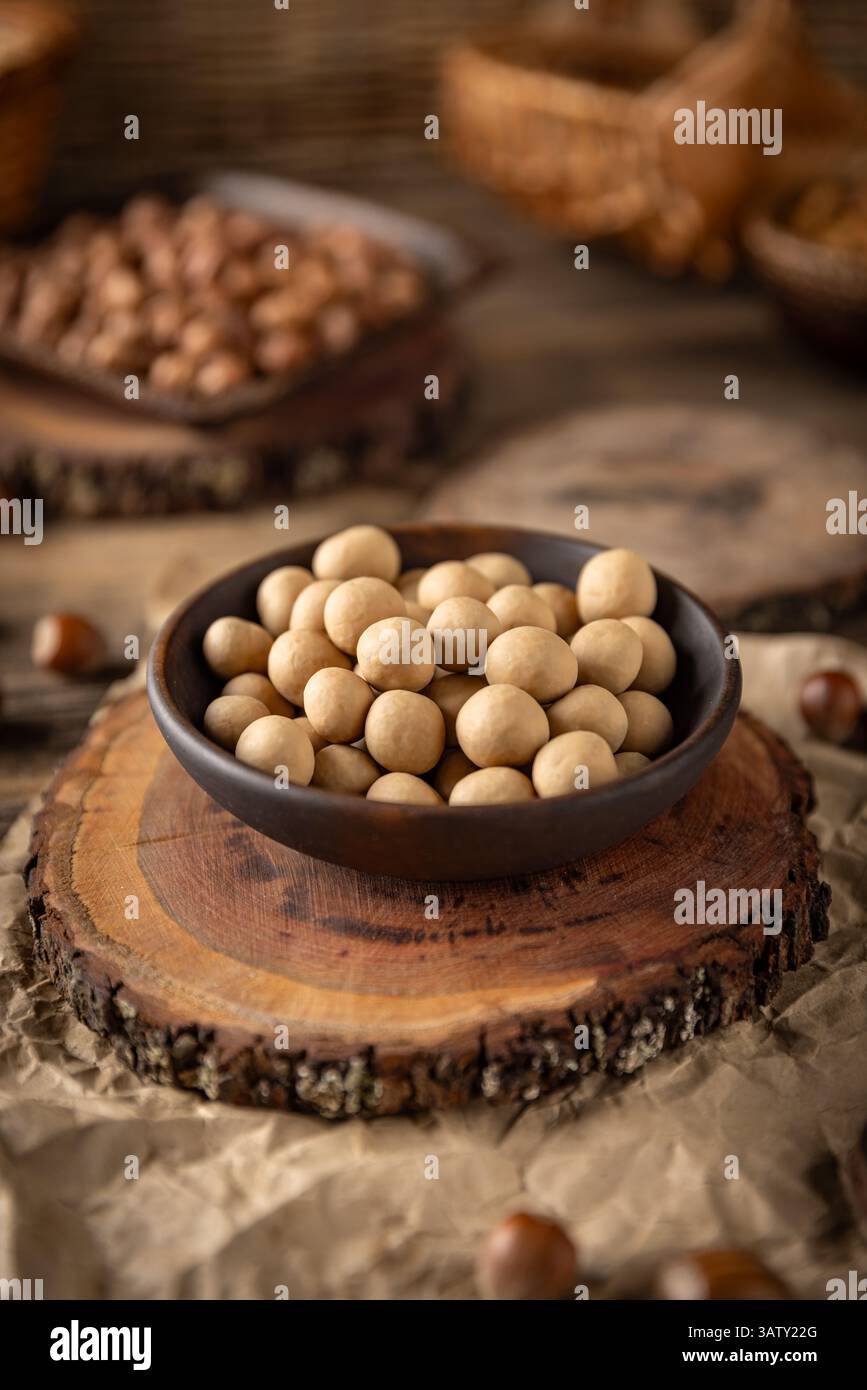 Noisettes grillées croquantes enrobées de chocolat blanc, servies dans un bol rustique, créant une délicieuse collation sucrée et salée Banque D'Images