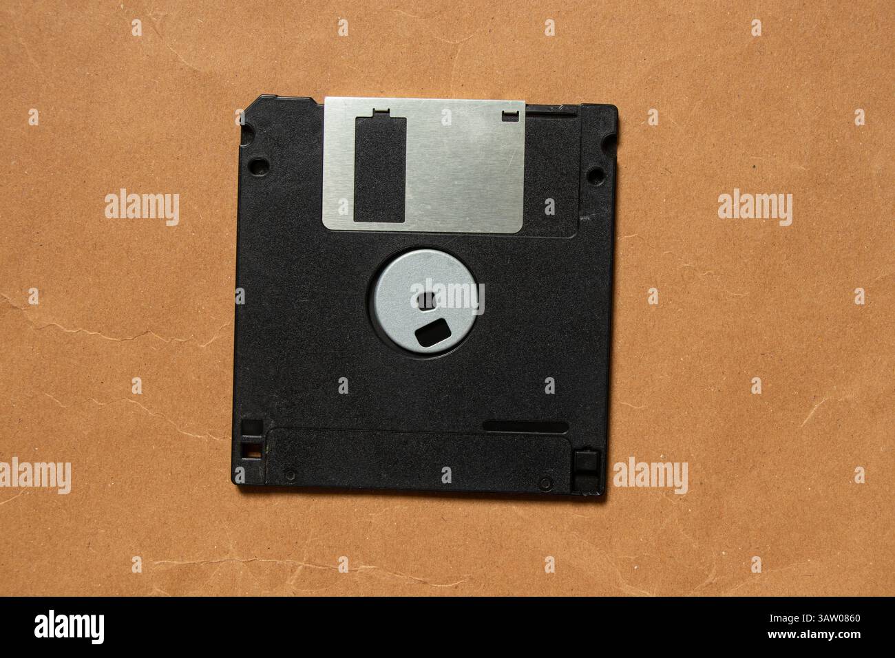Vieille disquette noire sur papier brun gros plan, vieille technologie Banque D'Images
