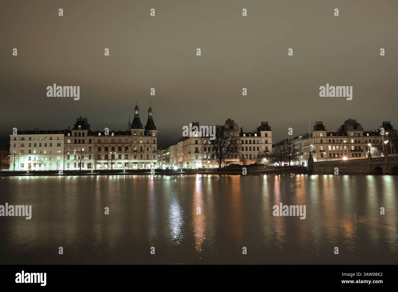 Une longue photographie d'exposition d'un couple de bâtiments à la rive d'un lac aléatoire dans un temps nuageux pendant la nuit à Copenhague Banque D'Images