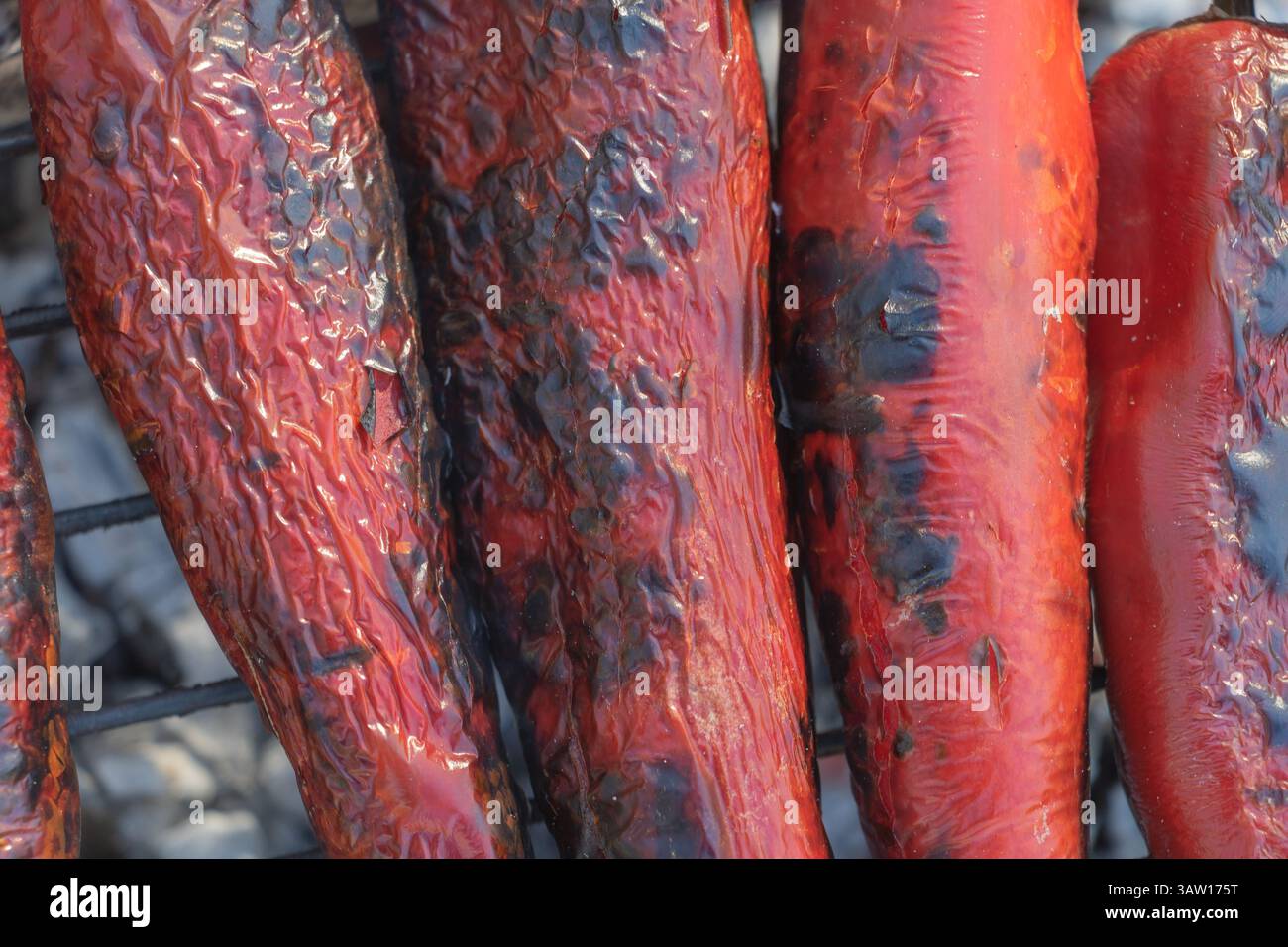 Gros plan de poivrons rouges suspendus au gril, avec des taches noires et carbonisées dessus. Banque D'Images