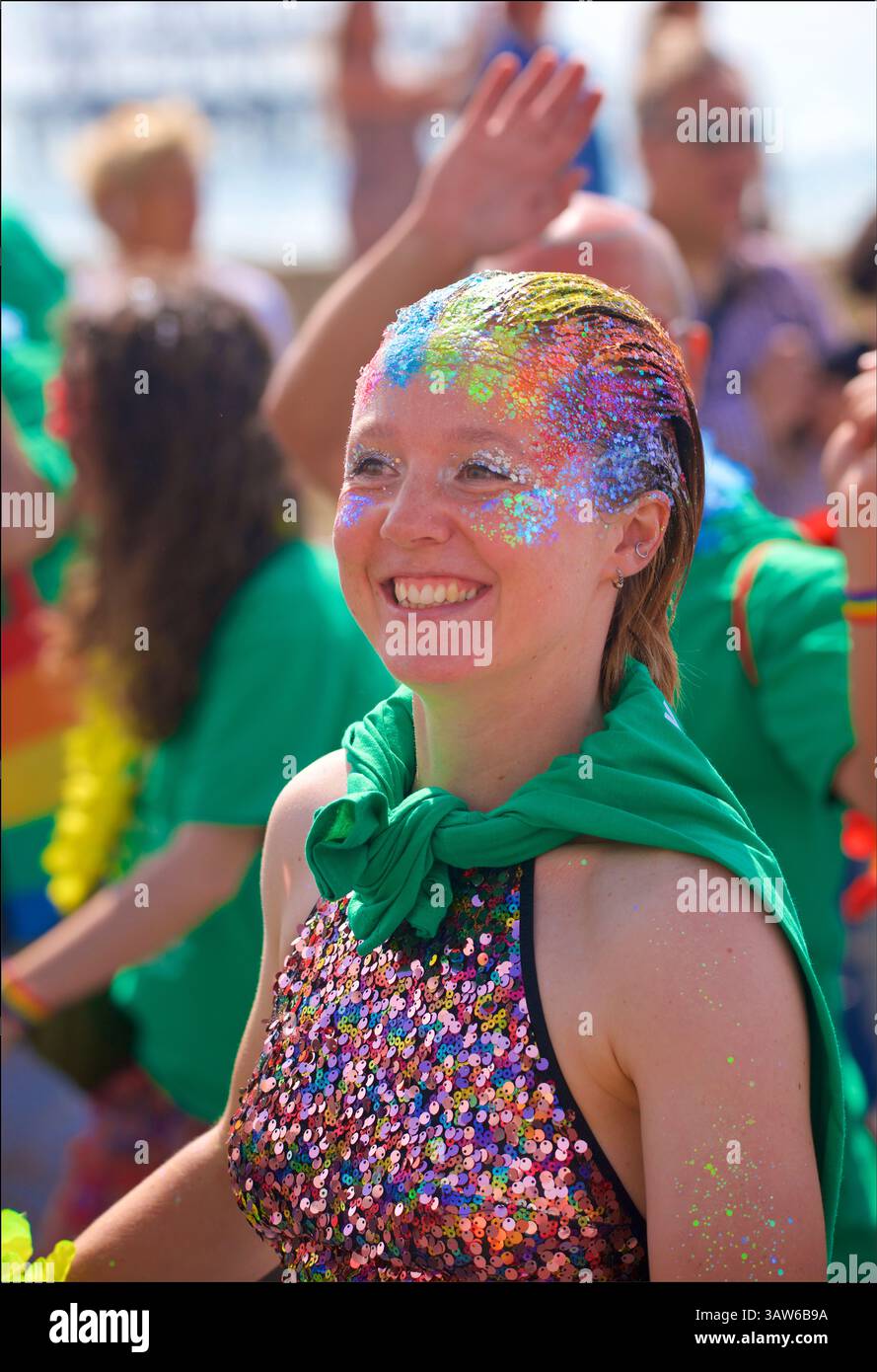 Femme souriante avec des paillettes colorées arc-en-ciel dans les cheveux, procession de Brighton Pride, août. Brighton et Hove, East Sussex, Angleterre, Royaume-Uni. Banque D'Images