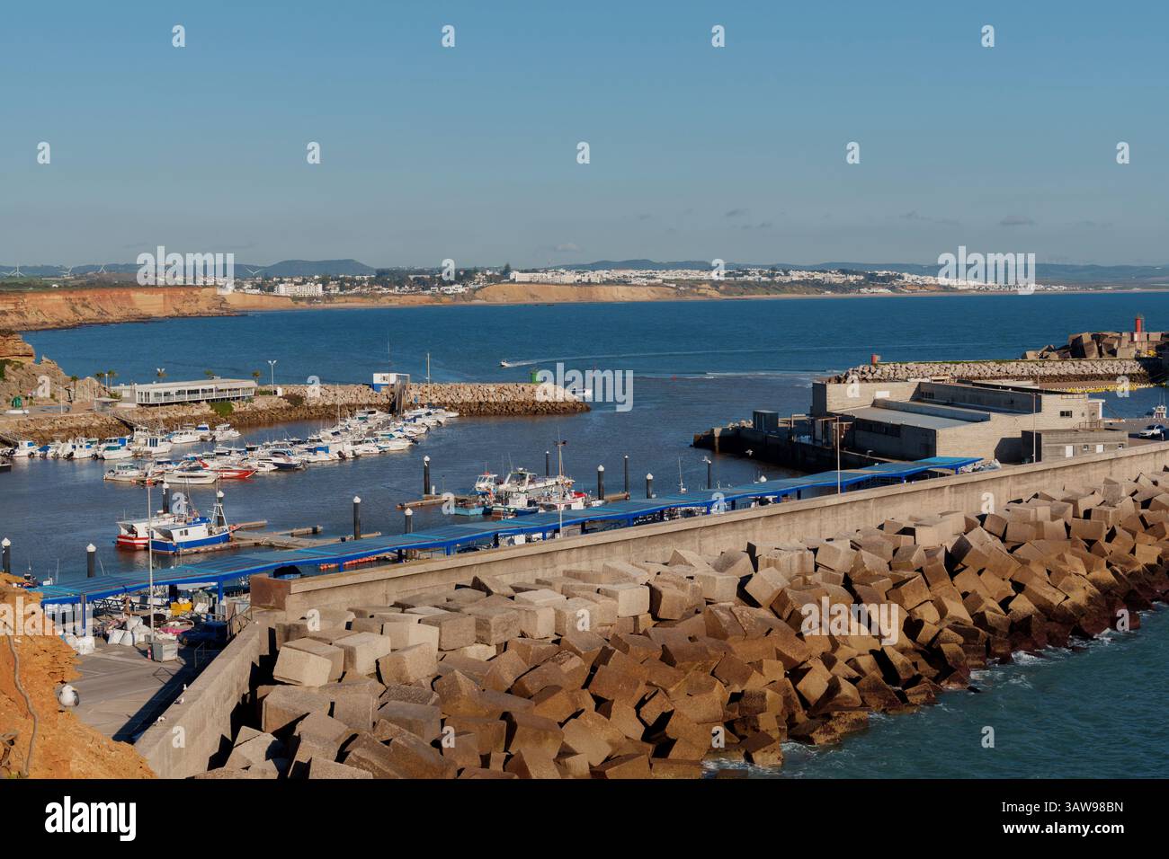 Les bateaux de pêche blancs et les bateaux de plaisance accostent dans une marina sur la côte de l'algarve par une journée ensoleillée Banque D'Images