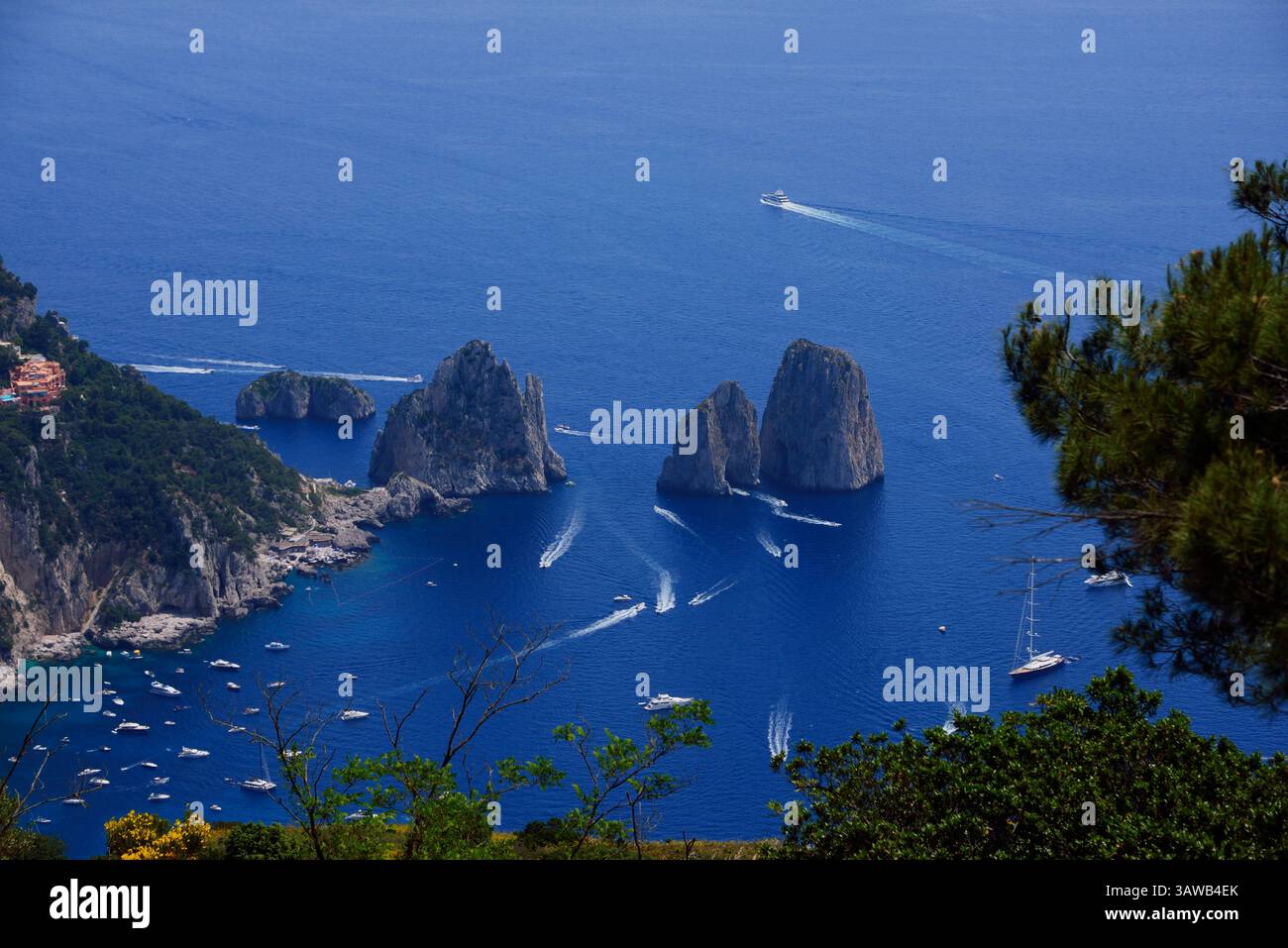 Une vue imprenable sur les formations rocheuses Faraglioni à Capri, en Italie, entourées d'eaux bleues vibrantes et d'une végétation luxuriante, les bateaux sur la mer Tyrrhénienne. Banque D'Images Une vue imprenable sur les formations rocheuses Faraglioni à Capri, en Italie, entourées d'eaux bleues vibrantes et d'une végétation luxuriante, les bateaux sur la mer Tyrrhénienne. Banque D'Images