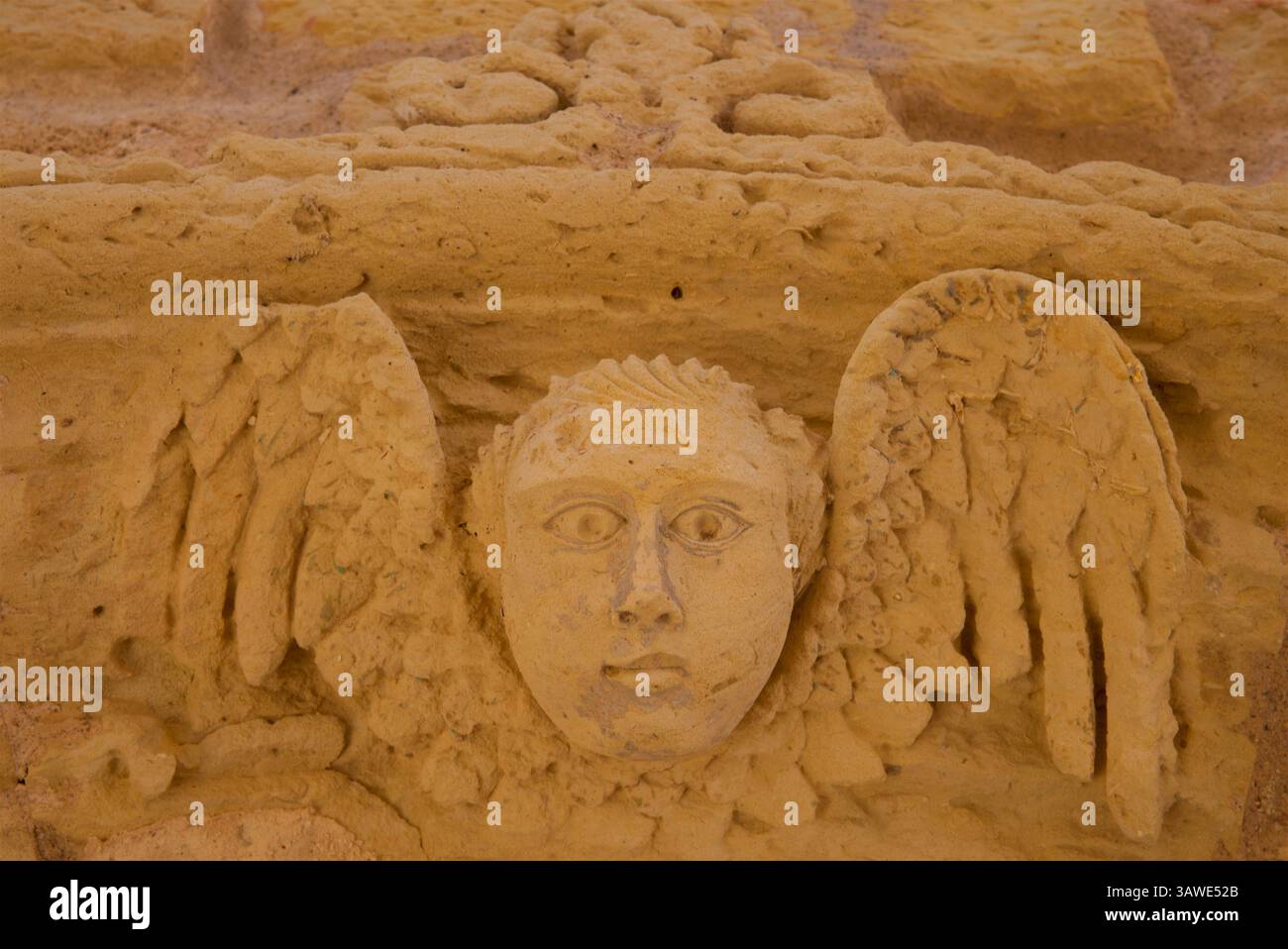 Détail d'un ange ailé sculpté au-dessus d'une porte sur un mur à Otrante, Province de Lecce, Italie du Sud. Le motif d'un visage d'ange avec des ailes sur sideÑoften appelé tête de chérubin ou ange ailé headÑhas signification culturelle et religieuse profonde, en particulier dans l'art et l'architecture chrétiens. Placer un tel motif au-dessus d'une porte pourrait symboliser la protection céleste, suggérant que le bâtiment est sous la surveillance de l'hôte céleste. Banque D'Images