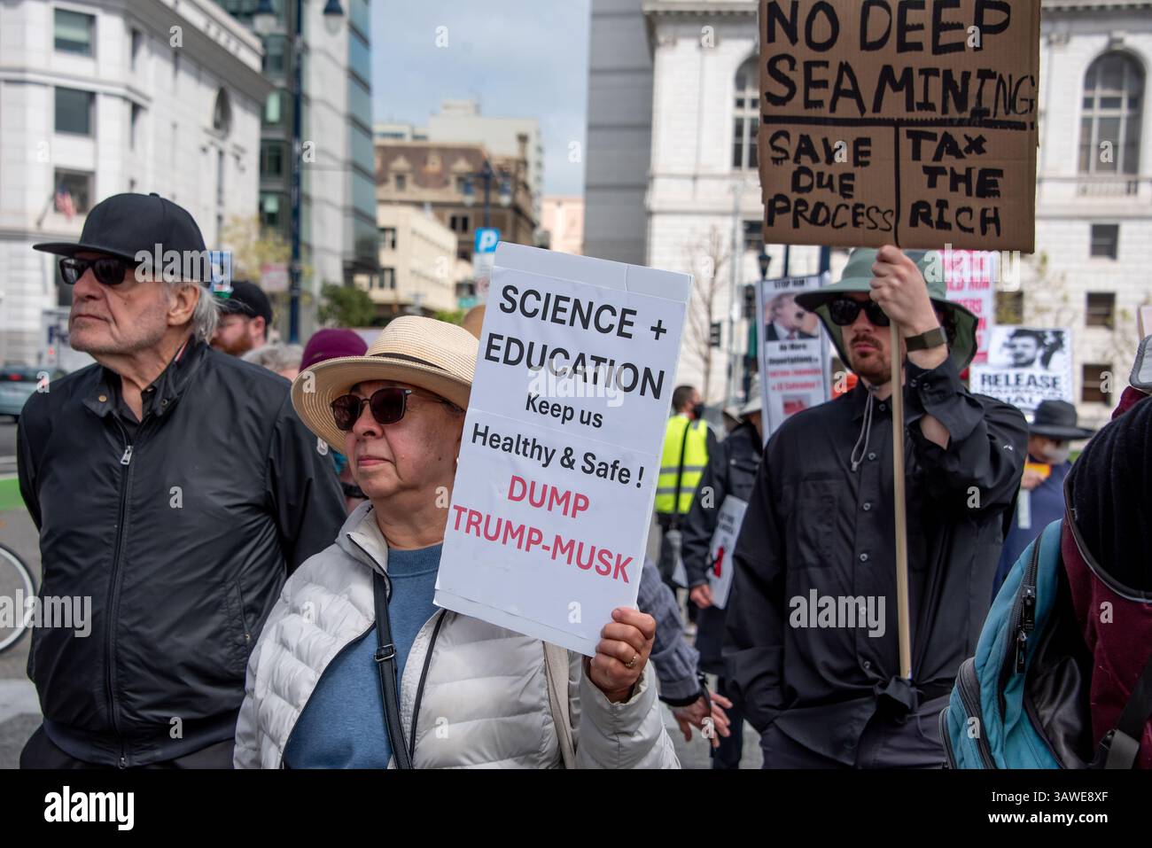 San Francisco, États-Unis. 19 avril 2025. Les manifestants écoutent des orateurs au Civic Center Plaza lors de la manifestation « Stop the Billionaire Agenda » contre l’administration Trump. Une femme tient un signe lisant, « Science + éducation nous garder en bonne santé et en sécurité ! Dump0 Trump-Musk », tandis qu'un homme derrière elle tient un panneau indiquant : « pas d'exploitation minière en haute mer. Enregistrez notre processus. Taxez les riches. » Crédit : Shelly Rivoli/Alamy Live News Banque D'Images
