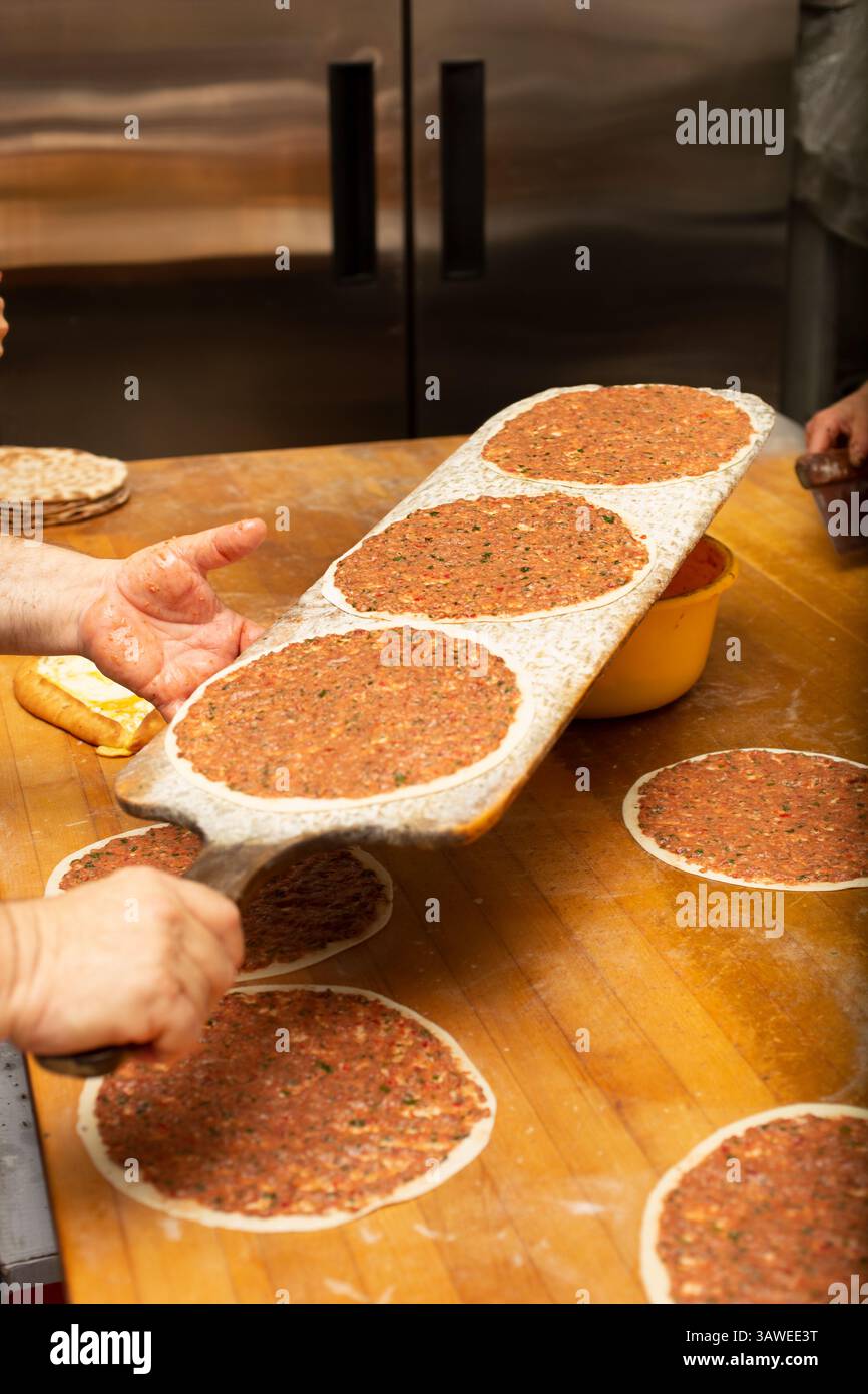Une vue du processus de fabrication de manakish sur une surface de table en bois, dans un cadre de cuisine de restaurant. Banque D'Images