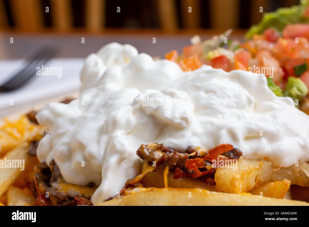 Vue rapprochée d'un gros tas de crème sure sur une entrée de frites carne asada. Banque D'Images