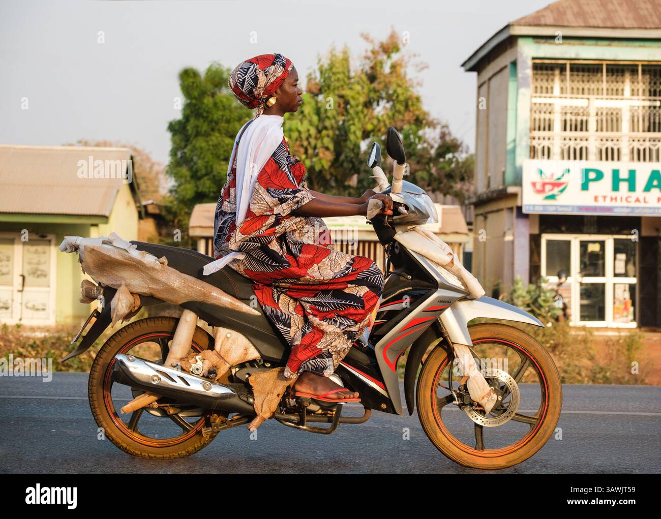 Ghana, Tamale. Circulation routière. Femme sur moto. Banque D'Images