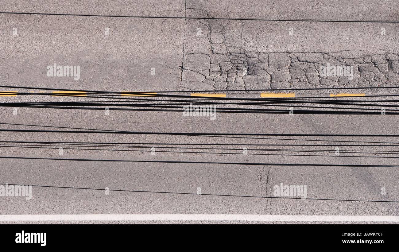 Vue aérienne de fils enchevêtrés et d'asphalte fissuré sur une route Banque D'Images
