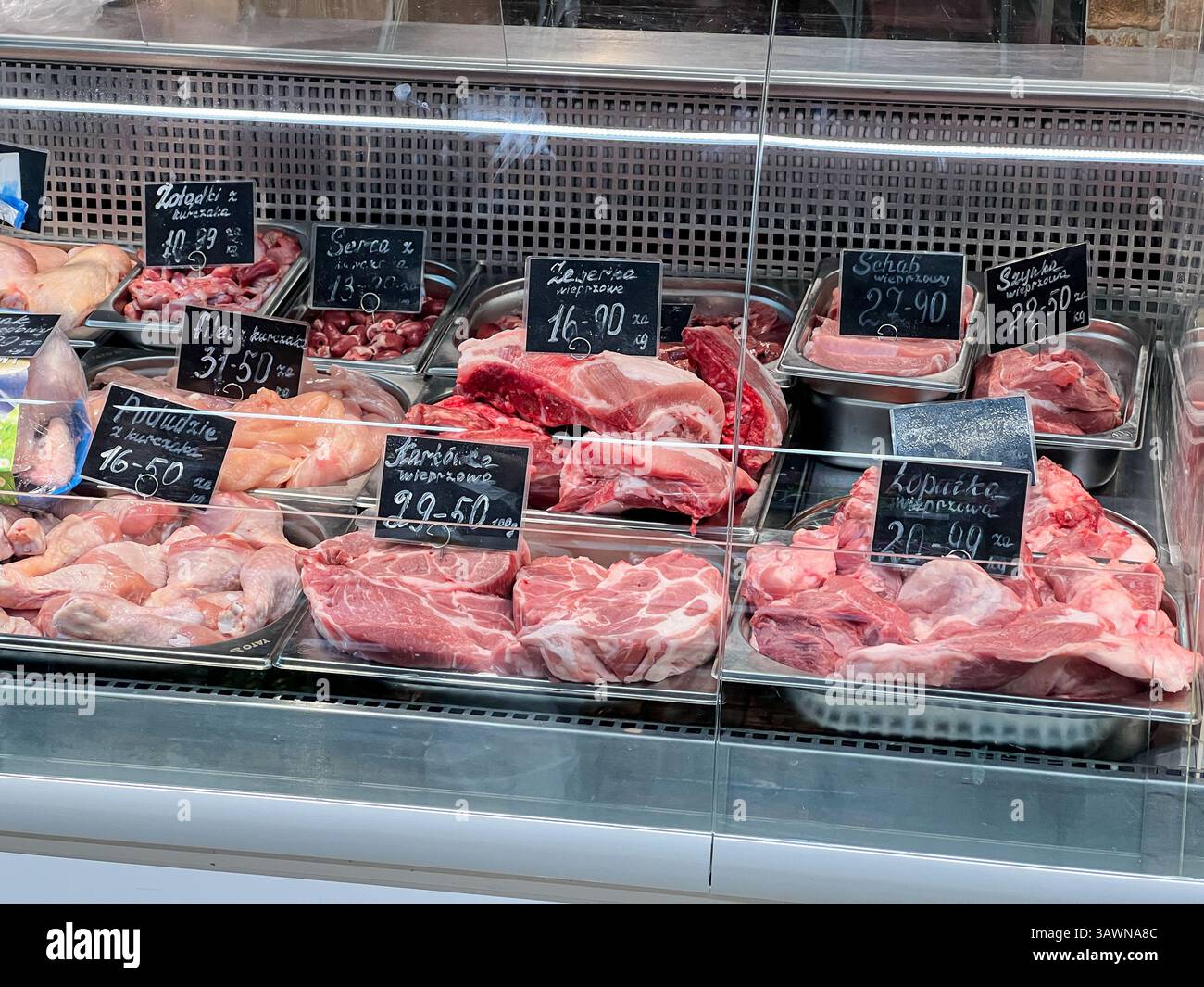 Poznan, Pologne - 18 avril 2025 : variété de viande de porc et de volaille crue fraîche exposée dans le comptoir en verre réfrigéré à la boucherie ou à l'épicerie w Banque D'Images