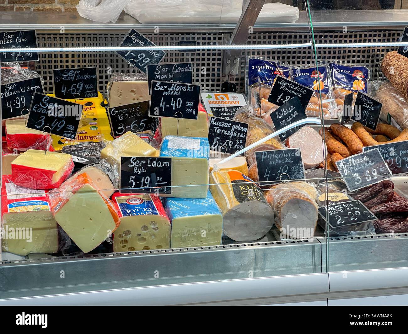 Poznan, Pologne - 18 avril 2025 : assortiment de fromages frais, saucisses et produits de charcuterie préparés soigneusement disposés dans une displa en verre réfrigérée Banque D'Images