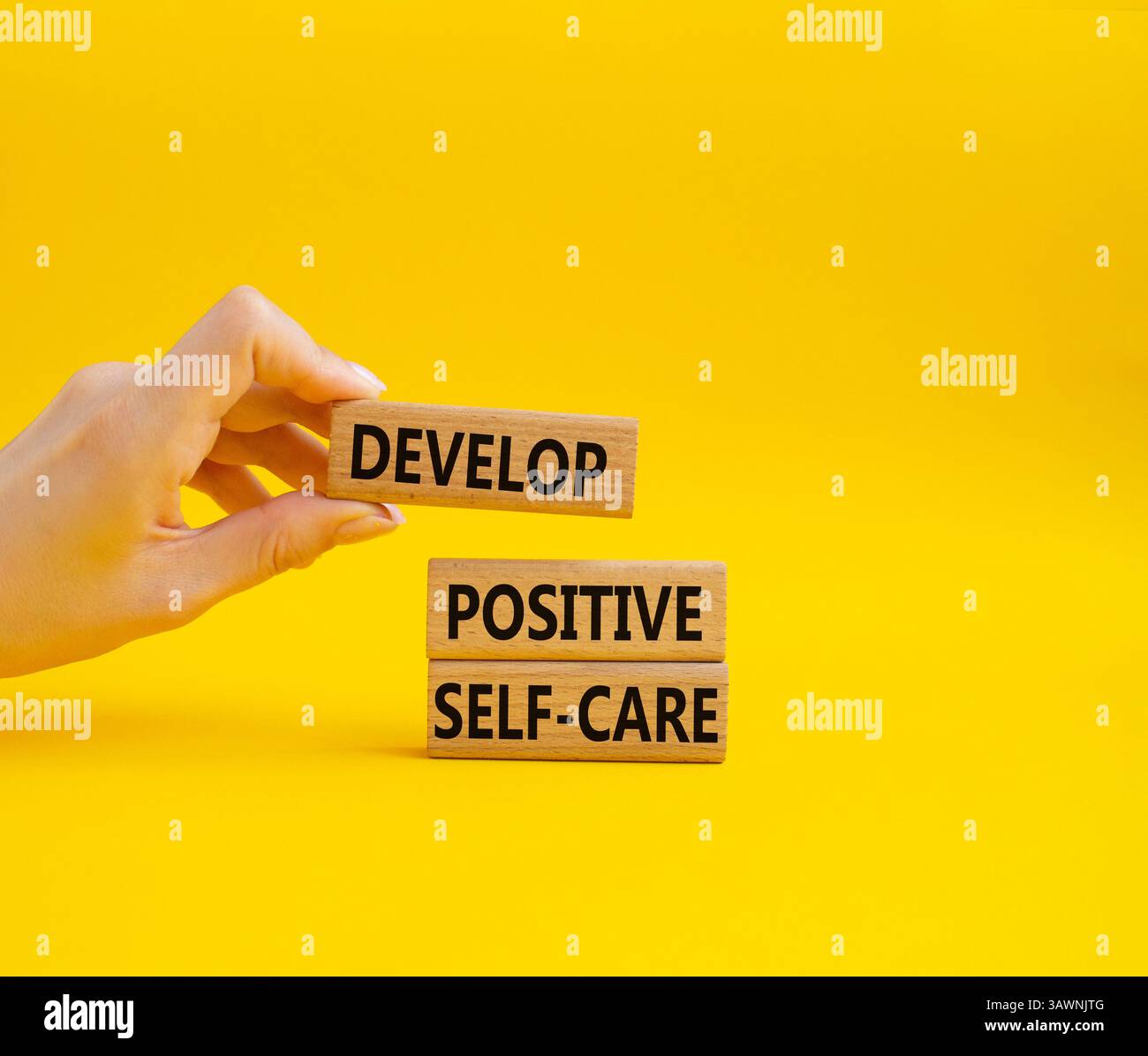 Développez un symbole d'autosoins positif. Les mots conceptuels développent un autosoin positif sur les blocs de bois. Beau fond jaune. Main d'homme d'affaires. Affaires Banque D'Images