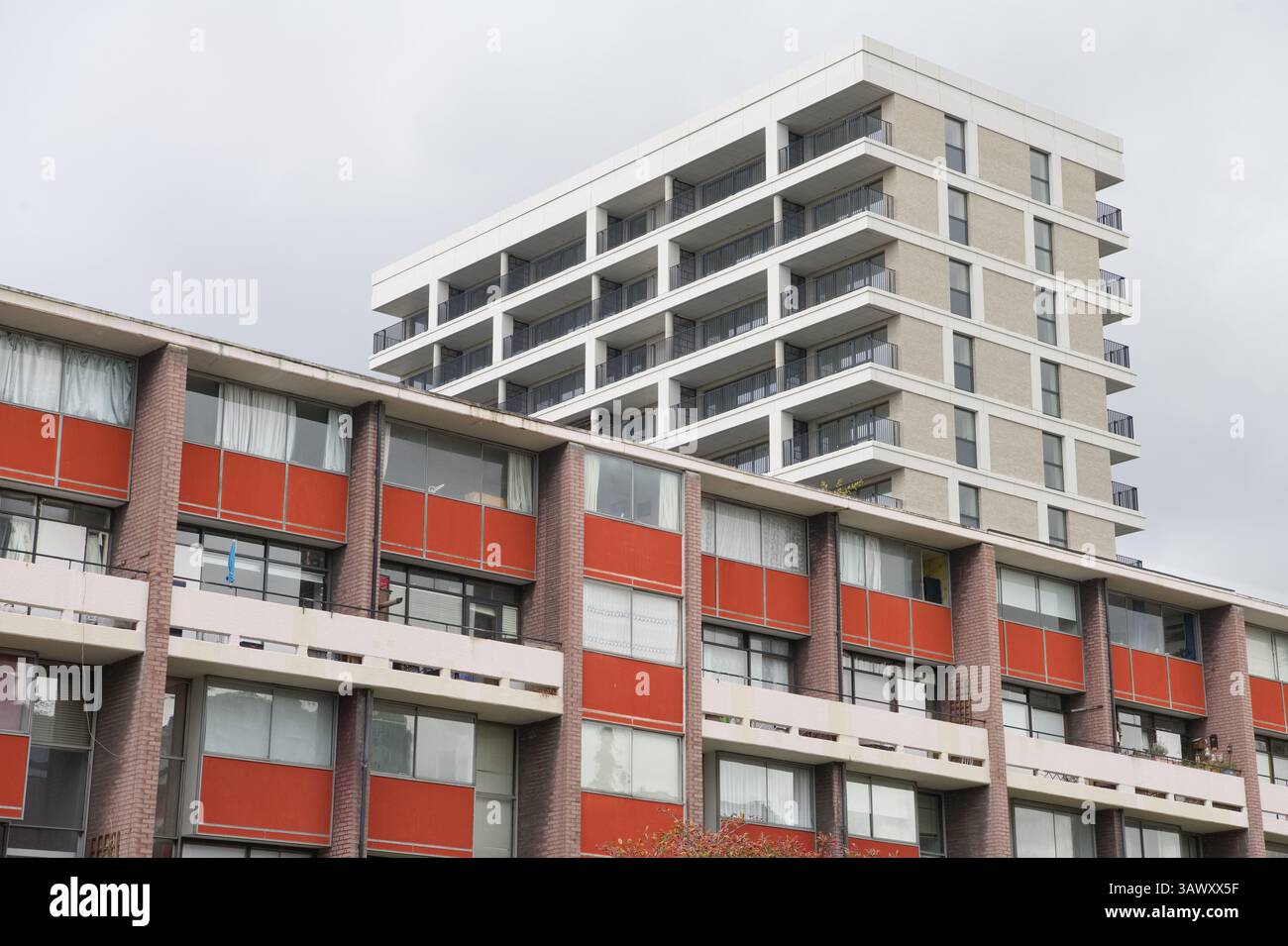 Appartements duplex rouges de Basterfield House dans le Golden Lane Estate dans la ville de Londres avec un bloc gris plus récent derrière Banque D'Images
