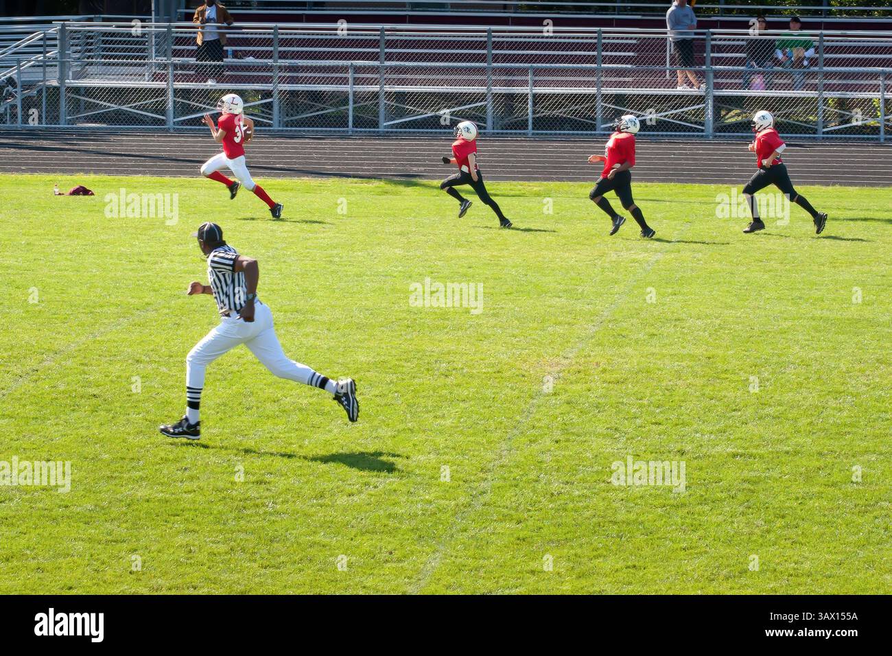 Match de football junior de lycée avec trois joueurs défensifs à la poursuite d'un running back avec une course officielle avec le jeu. Banque D'Images Match de football junior de lycée avec trois joueurs défensifs à la poursuite d'un running back avec une course officielle avec le jeu. Banque D'Images