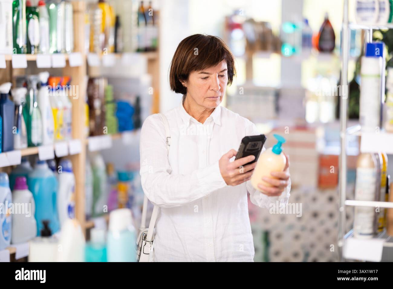 Femme âgée scannant le code qr pour le savon liquide Banque D'Images