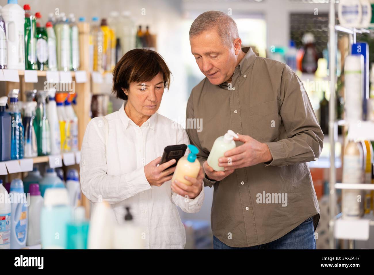 Couple homme et femme scannant le code qr pour le savon liquide Banque D'Images