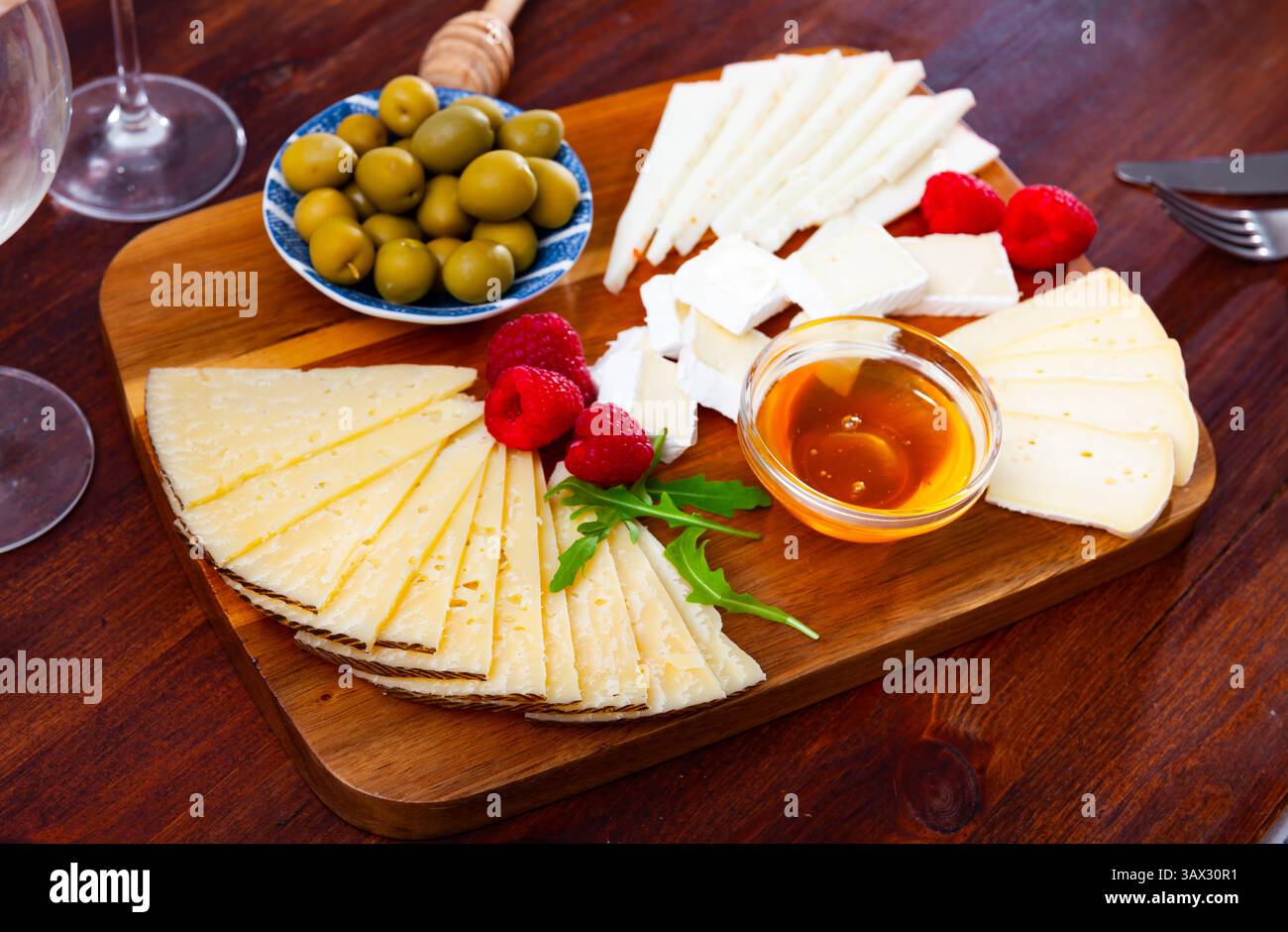 Différents types de fromage, miel, framboises et olives sur bois Banque D'Images