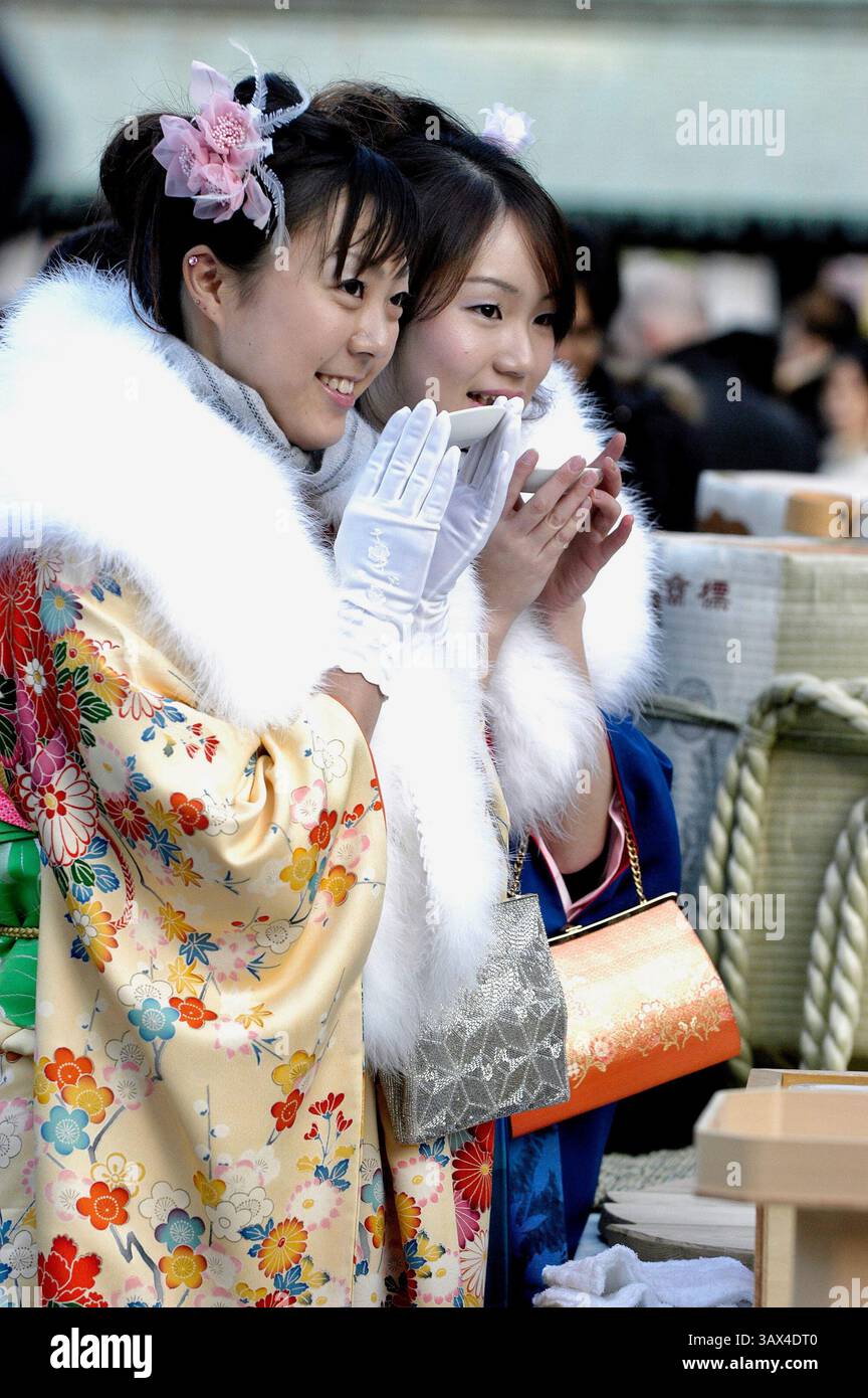 Deux japonaises vêtues de kimono sirotent du vin de riz au saké dans un sanctuaire de Tokyo, au Japon. Alors que 20 est l'âge officiel où les jeunes Japonais peuvent boire de l'alcool, smo Banque D'Images