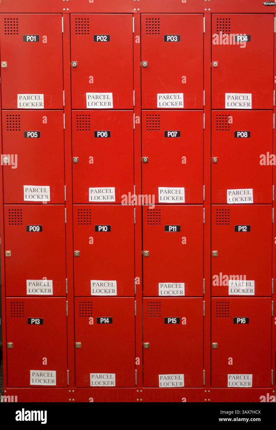 Casiers à colis rouge vif soigneusement disposés en rangées d'un service postal dans une zone urbaine animée Banque D'Images