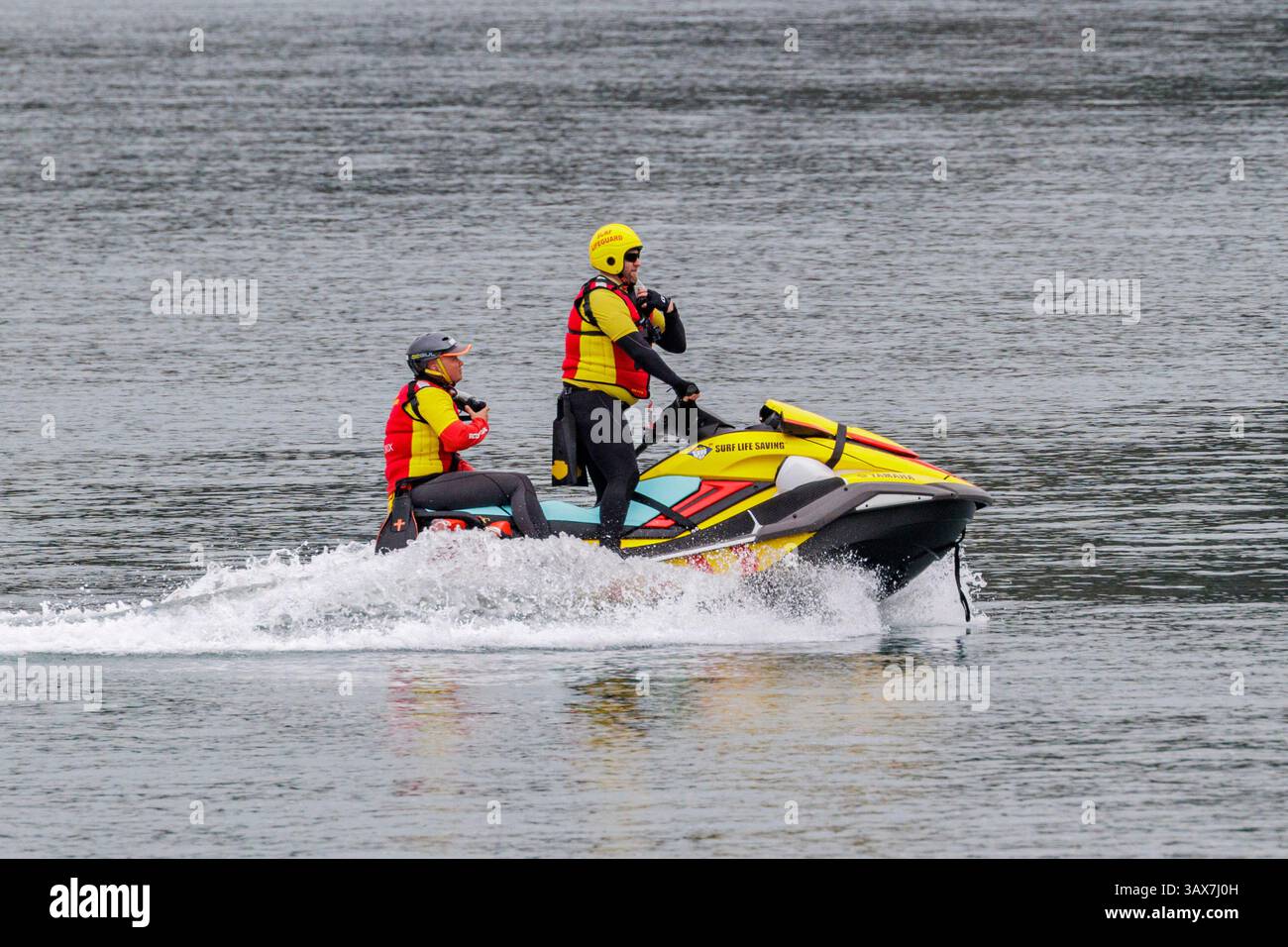 Deux membres de l'équipe de sauvetage naviguent à bord d'une motomarine personnelle sur une étendue d'eau tranquille par un après-midi couvert Banque D'Images