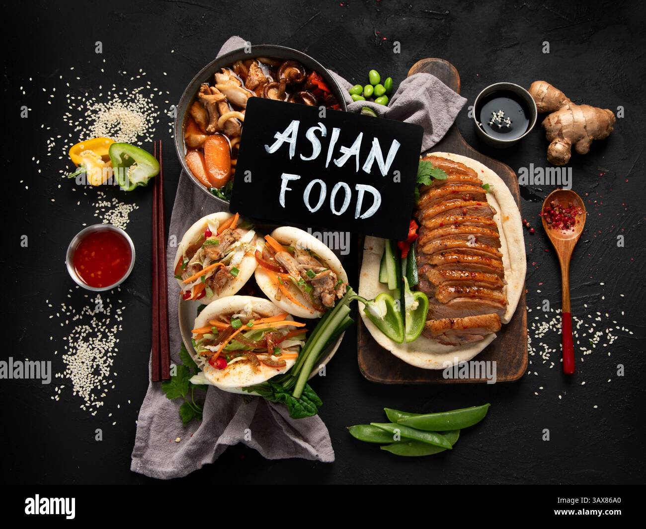 Ensemble de plats chinois sur fond sombre : canard aigre-doux, soupe de nouilles, petits pains cuits à la vapeur. Banquet ou buffet asiatique, vue de dessus. Banque D'Images