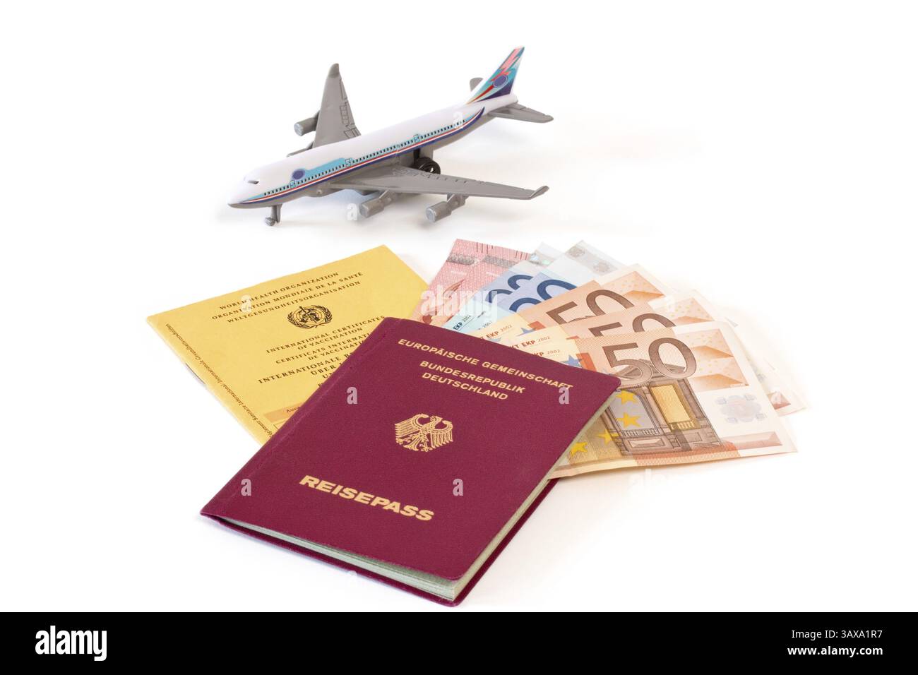 Passeport allemand, carte de vaccination et argent comptant avec avion jouet sur fond blanc passeport allemand, carte de vaccination et argent comptant avec avion jouet sur whit Banque D'Images