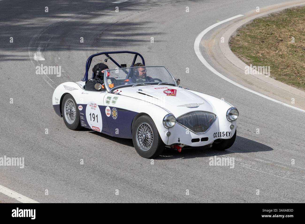 Le Valtin, France - 9 avril 2025 : vue sur une Austin-Healey 100-4 blanche et bleue conduisant sur une route. Banque D'Images