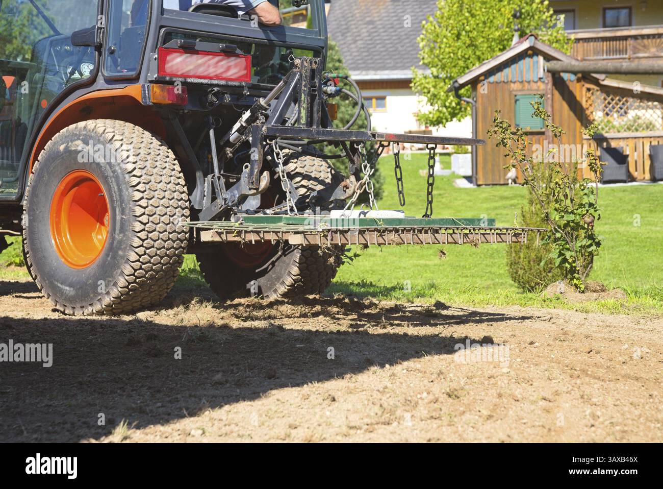 Petit tracteur avec herse à dents pendant le travail du sol - le hersage Banque D'Images