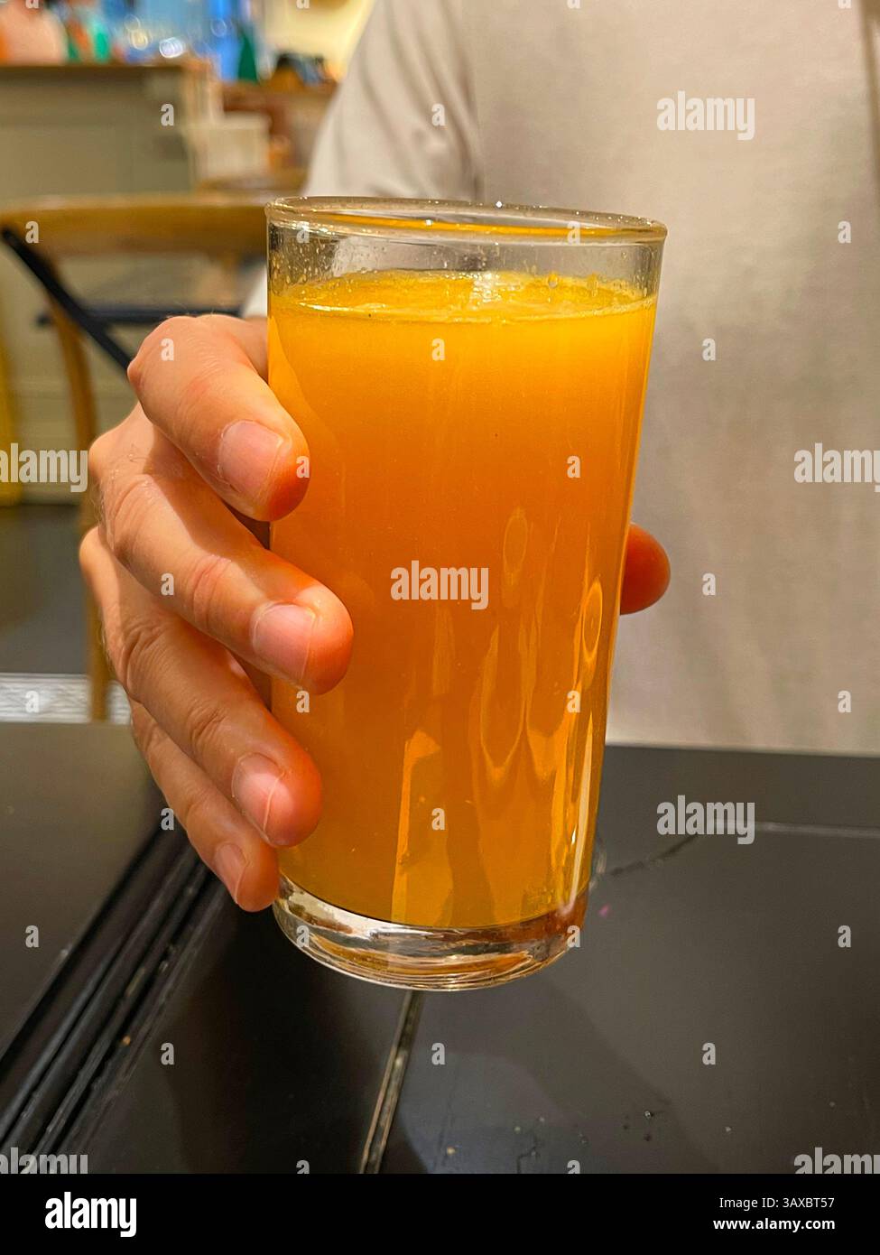 Main tenant un verre de jus d'orange. - Image de stock capturée avec un smartphone