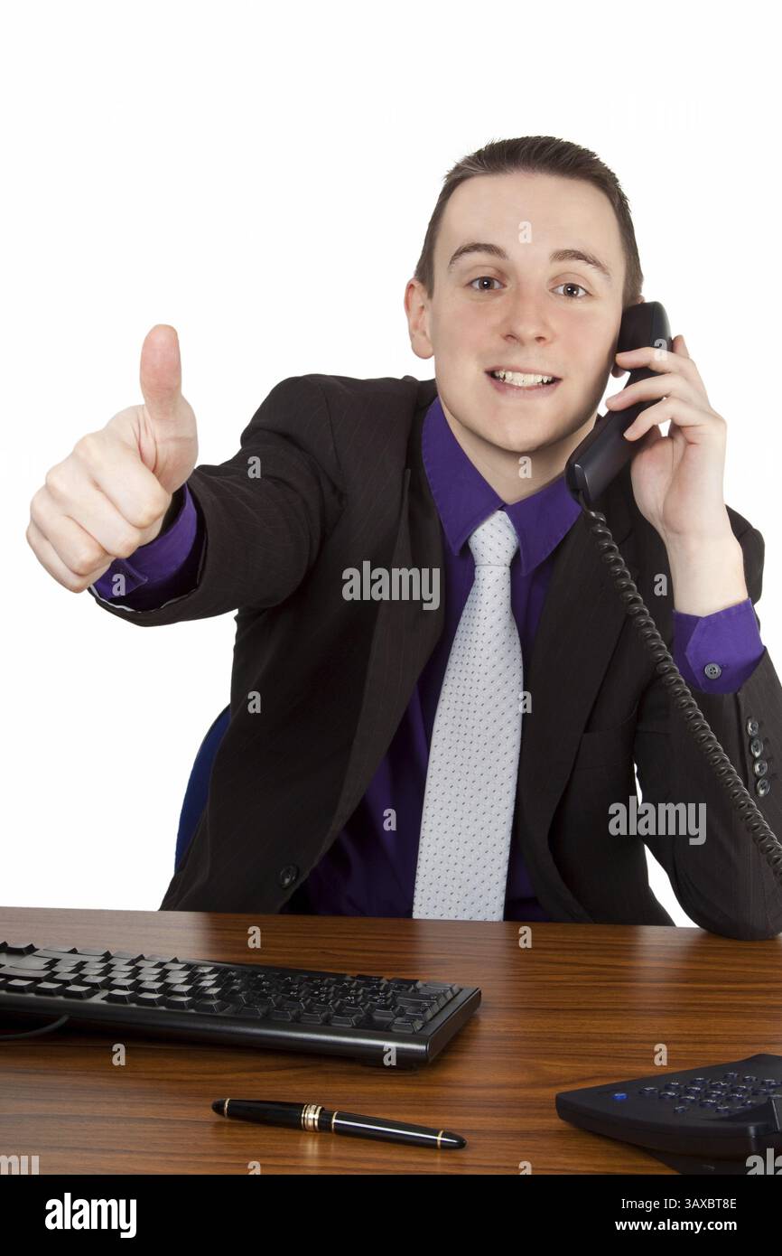 Jeune homme d'affaires au téléphone tenant les pouces vers le haut - isolé jeune homme d'affaires au téléphone montrant les pouces vers le haut - isolé Banque D'Images