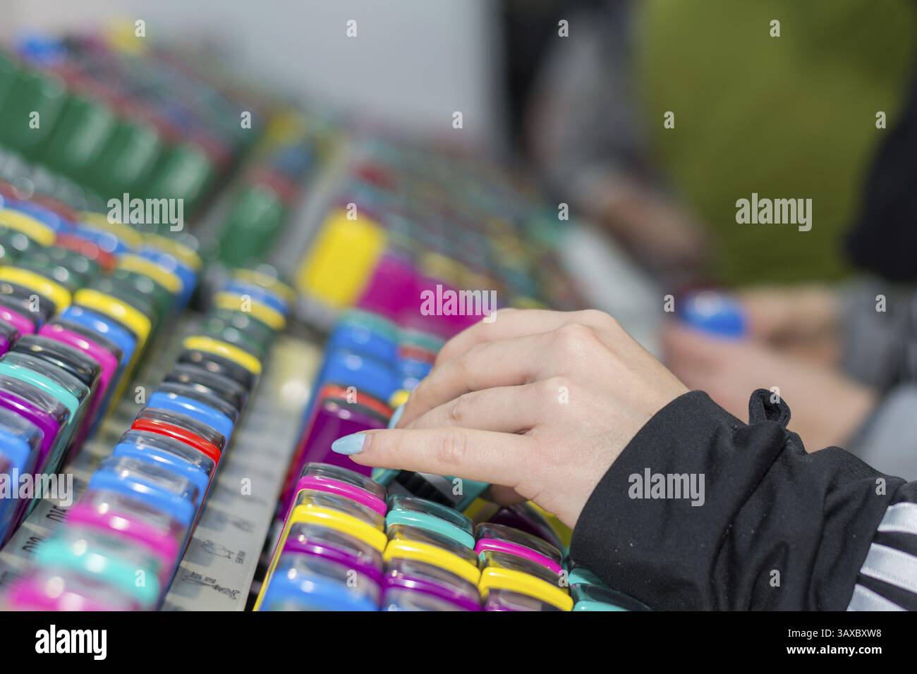 Personne avec des ongles peints regardant dans des timbres colorés pour enfants Banque D'Images