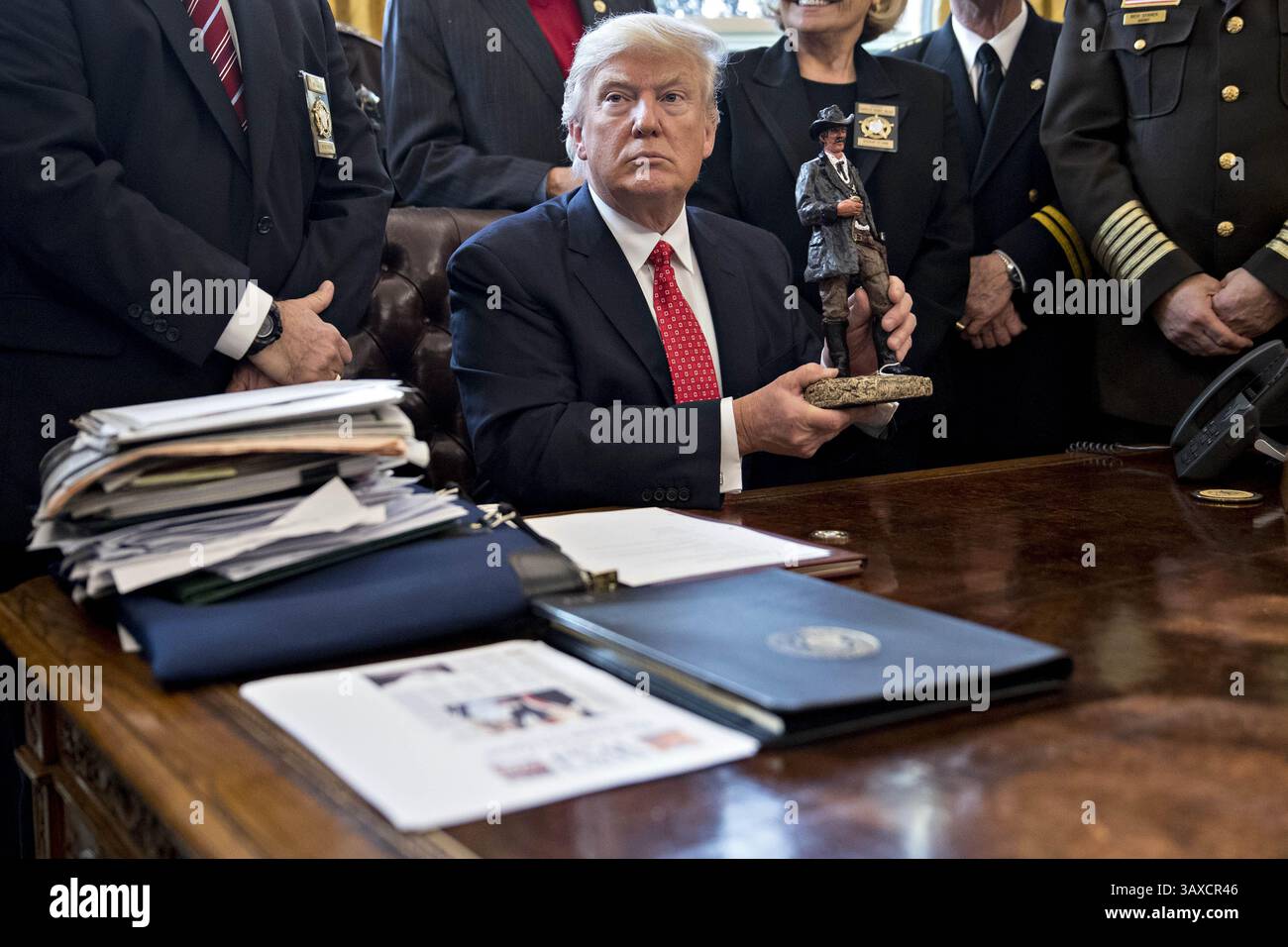 7 février 2017 - Washington, District of Columbia, États-Unis d'Amérique - le président américain Donald Trump tient une statue qu'il a reçue en cadeau lors d'une rencontre avec les shérifs du comté dans le bureau ovale de la Maison Blanche à Washington, DC, États-Unis, le mardi 7 février, 2017. L’administration Trump reviendra devant les tribunaux mardi pour faire valoir qu’elle a une large autorité sur la sécurité nationale et pour exiger le rétablissement d’une interdiction de voyager sur sept pays à majorité musulmane qui ont bloqué des réfugiés, déclenché des manifestations et remis au jeune gouvernement son premier test crucial. . Crédit : Andrew Harrer / piscine via CNP ( Banque D'Images