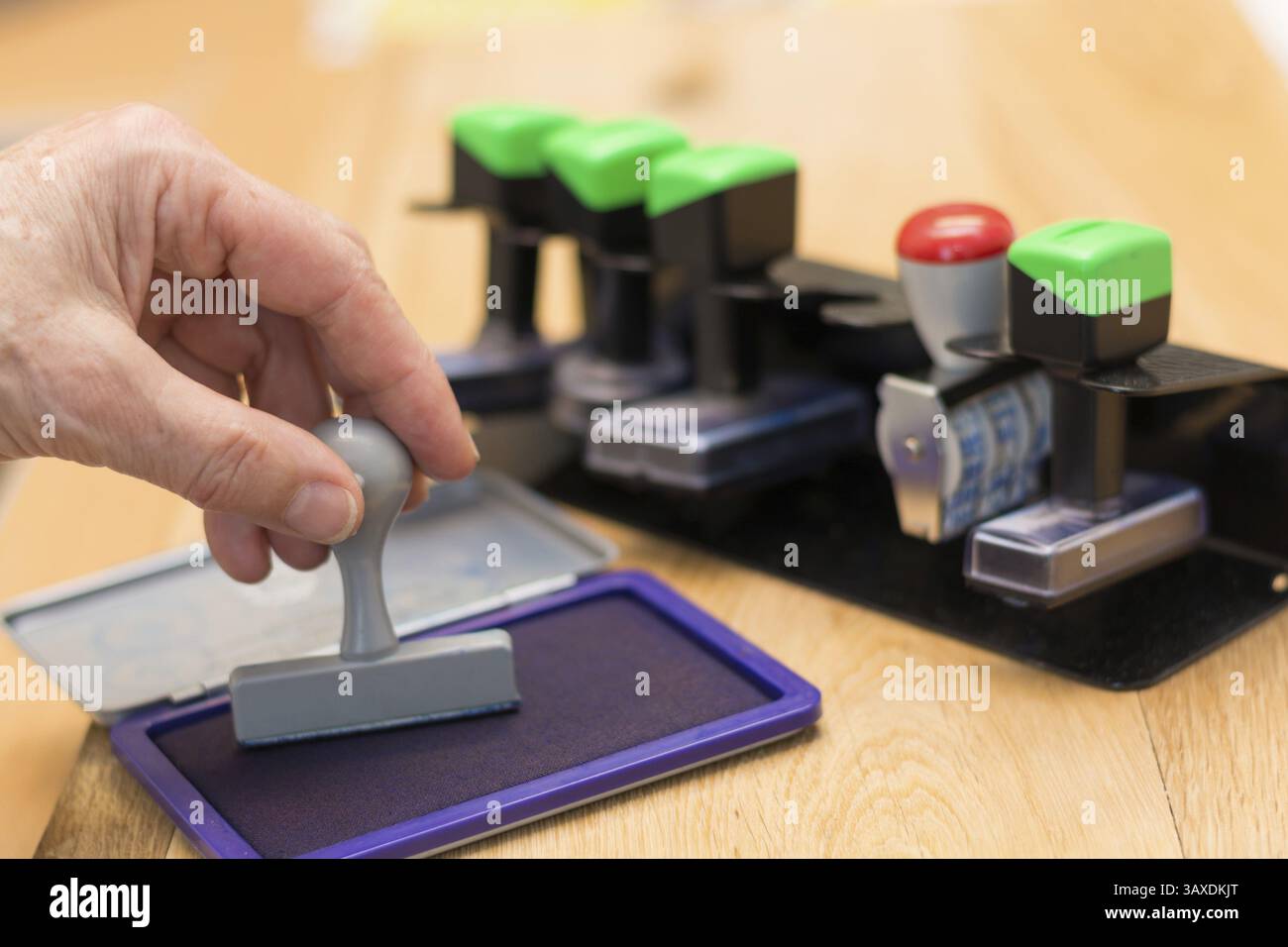 La personne presse le timbre dans le tampon encreur, derrière eux d'autres timbres sur le porte-timbre Banque D'Images