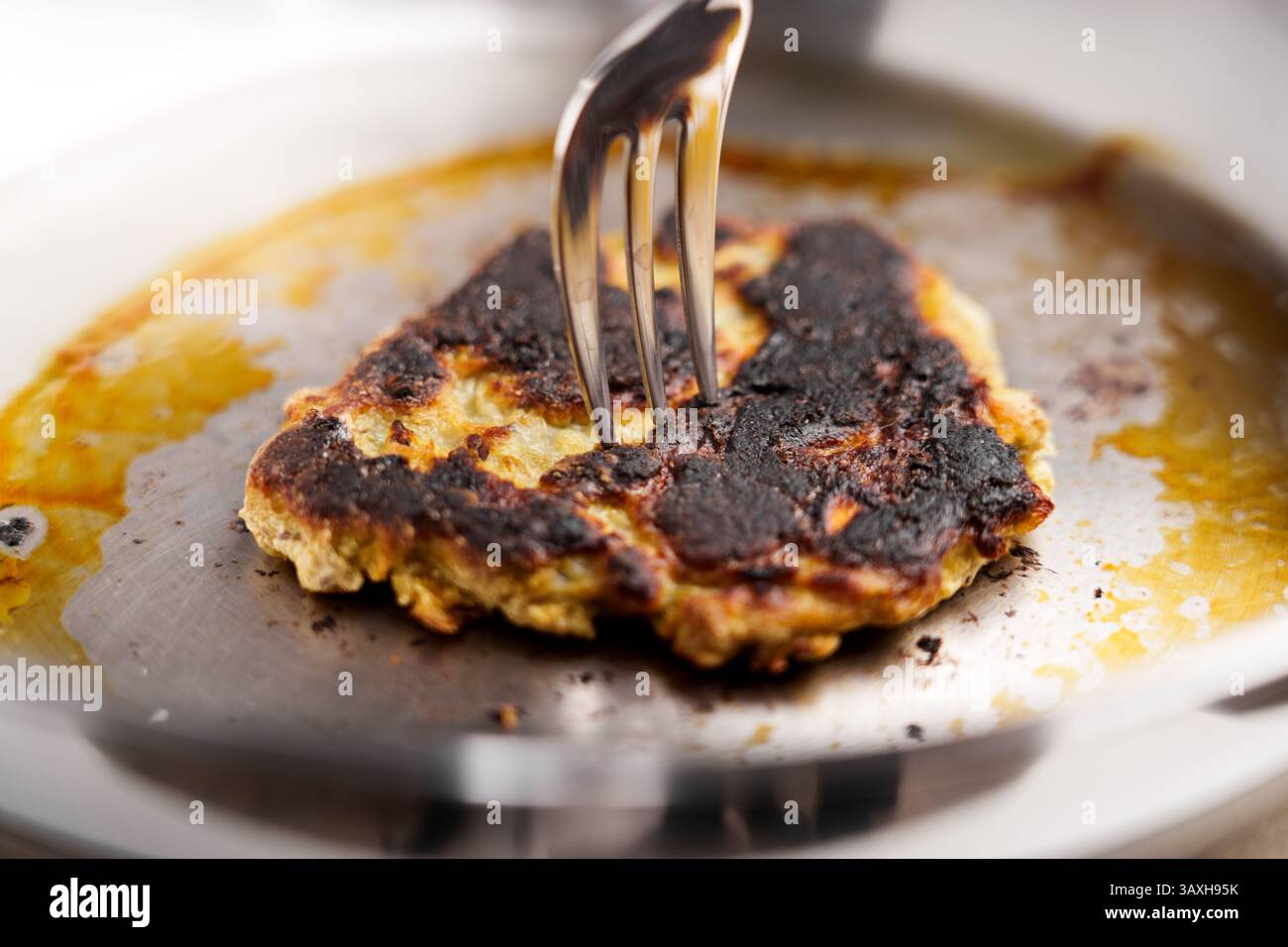 Ramasser une crêpe brûlée de la poêle à l'aide d'une fourchette. Prise de vue macro Banque D'Images