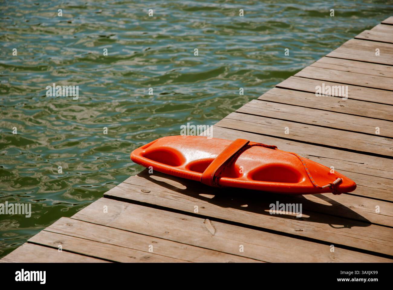 Flotteur de sauvetage de sauveteur sur quai en bois près de la surface de l'eau du lac en été. Concept week-end près de la forêt et du lac. Banque D'Images