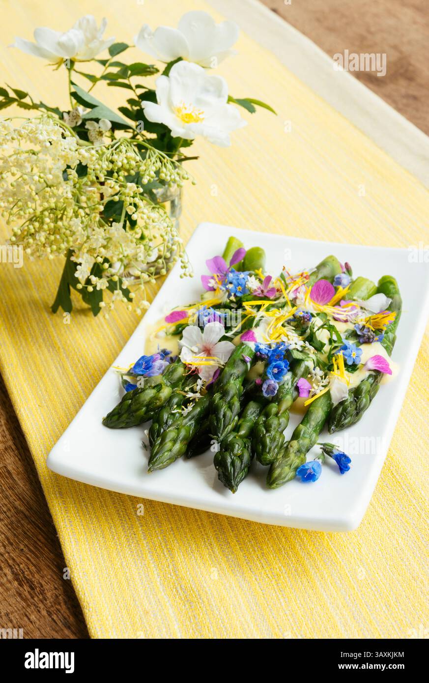 Asperges vertes avec une sauce safran et des fleurs comestibles. Banque D'Images