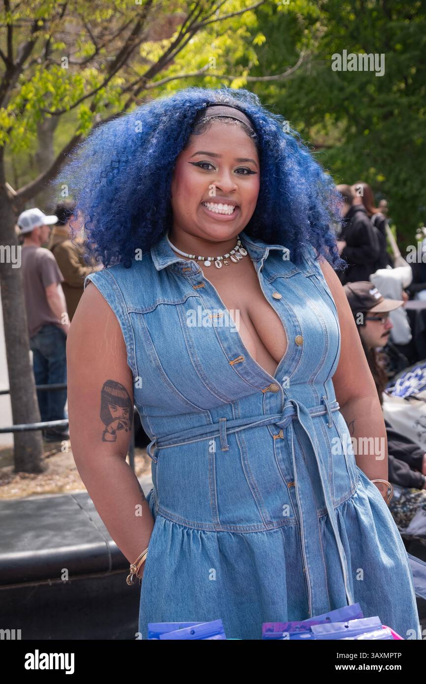 Un joli vendeur au 2025 420 pot Smoke-in à Greenwich Village, Manhattan, NYC. Elle avait de gros cheveux bleus et une robe en denim coupe basse. Banque D'Images