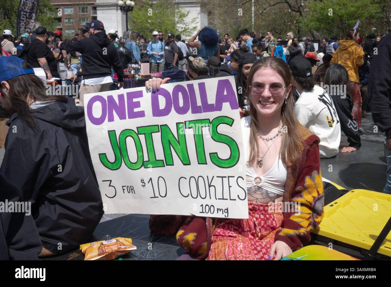 Au 420 pot Smoke-in dans le Village de Washington Square Park, un joli vendeur tient une pancarte annonçant des joints de dollar et des biscuits de pot. Banque D'Images