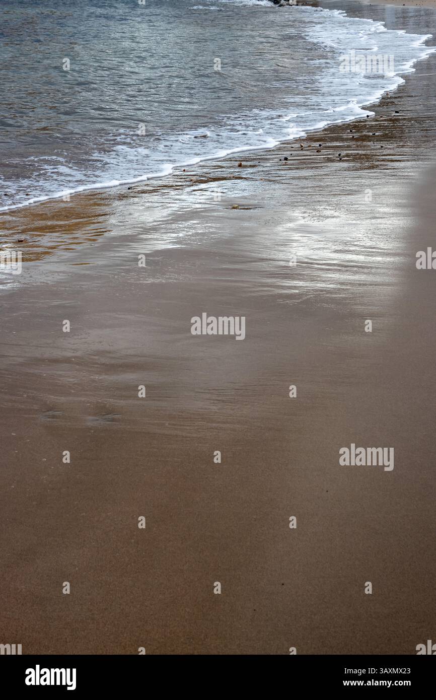 Plage de sable en début de soirée, lorsque le soleil est bas. Ligne de la marée et reflet du soleil, du ciel et des nuages. Playa del Cabron, Las Palmas, G. Banque D'Images