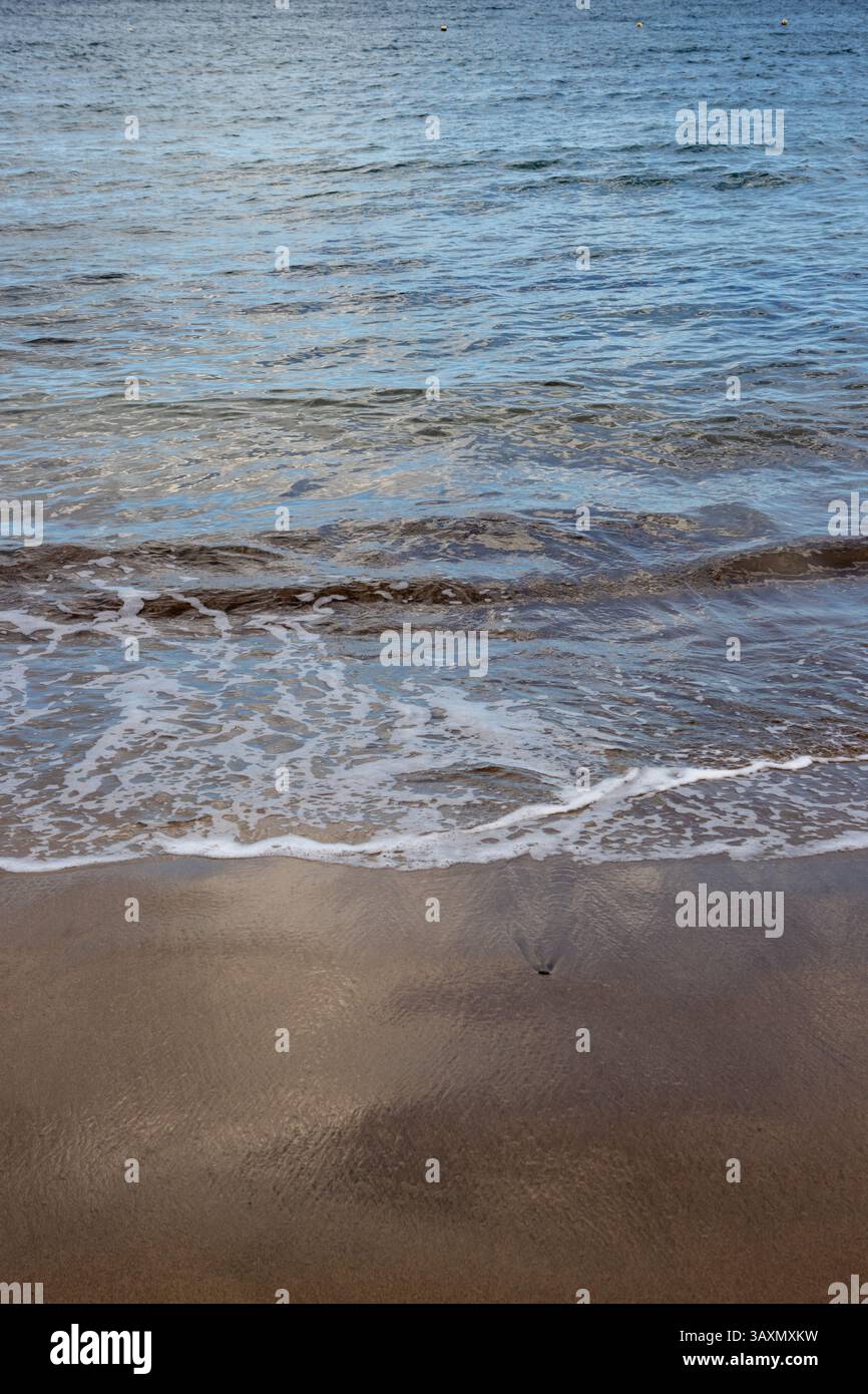 Plage de sable en début de soirée, lorsque le soleil est bas. Ligne de la marée et reflet du soleil, du ciel et des nuages. Playa del Cabron, Las Palmas, G. Banque D'Images