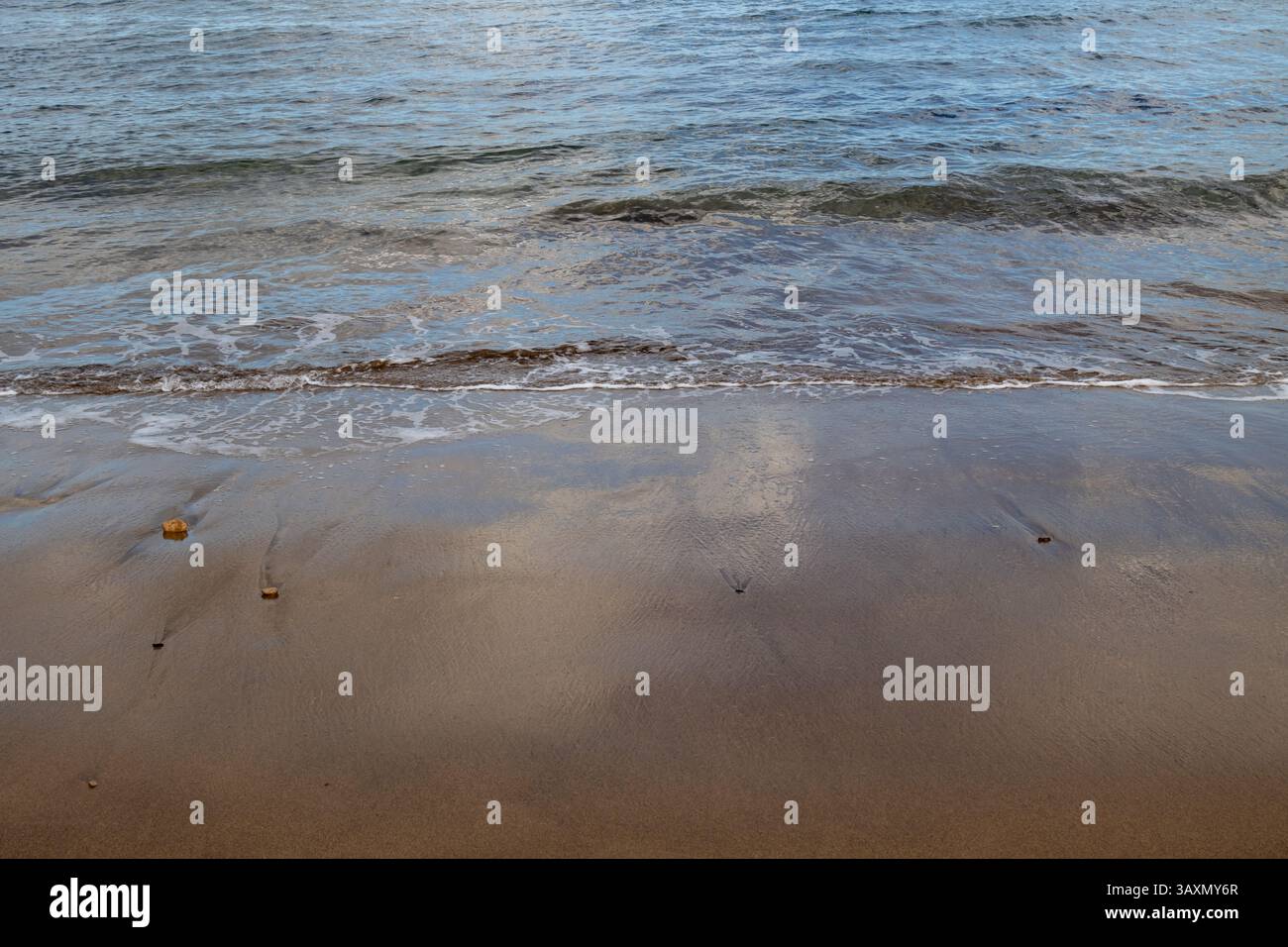 Plage de sable en début de soirée, lorsque le soleil est bas. Ligne de la marée et reflet du soleil, du ciel et des nuages. Playa del Cabron, Las Palmas, G. Banque D'Images