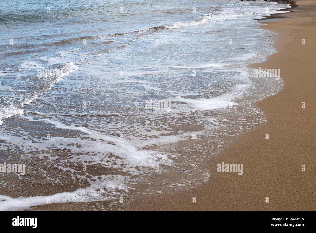 Plage de sable en début de soirée, lorsque le soleil est bas. Ligne de la marée et reflet du soleil, du ciel et des nuages. Playa del Cabron, Las Palmas, G. Banque D'Images